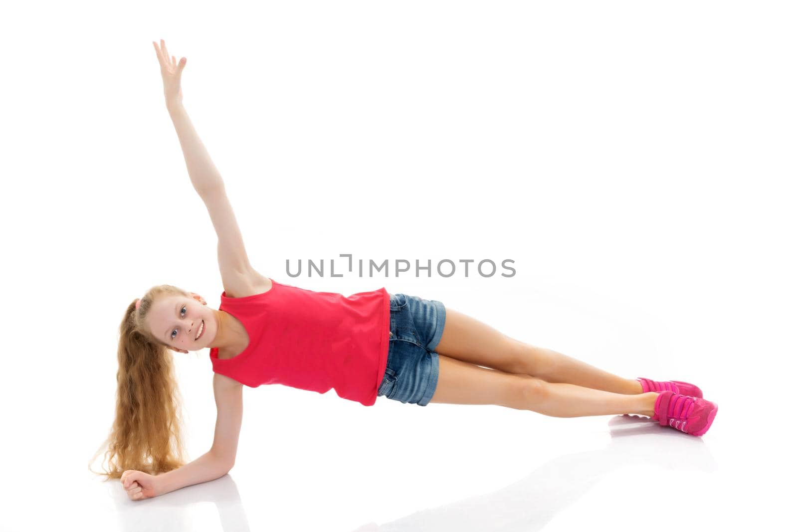 A girl gymnast performs an acrobatic element on the floor. The concept of childhood, sport, healthy lifestyle. Isolated on white background.