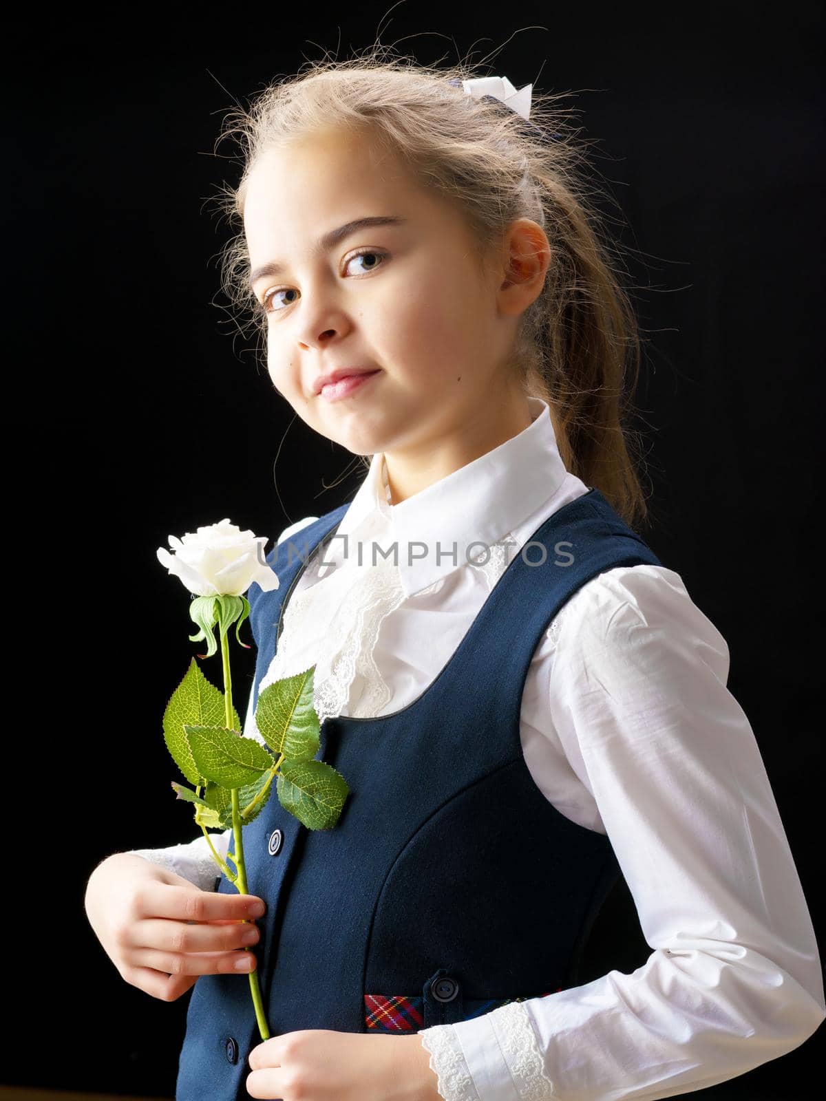 Beautiful little girl with a flower in her hand. The concept of style and fashion. On a black background.