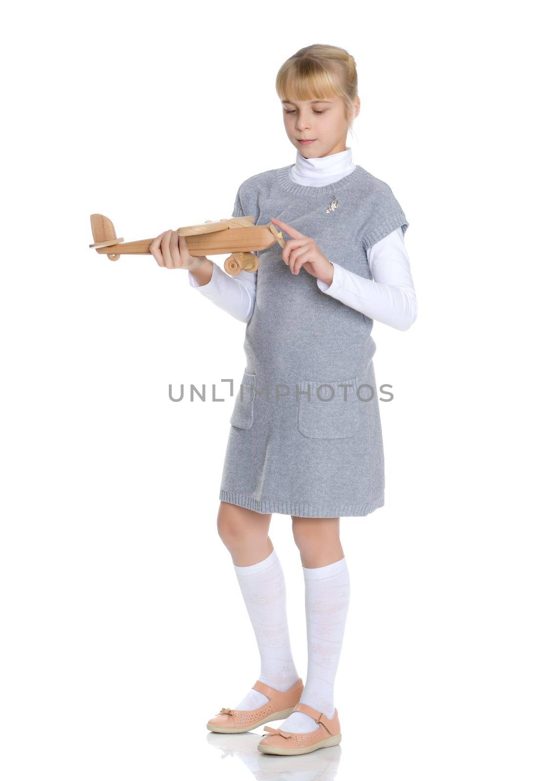 Happy little girl is playing with a wooden plane in the studio on a white background. The concept of emotions and children's games. Isolated.