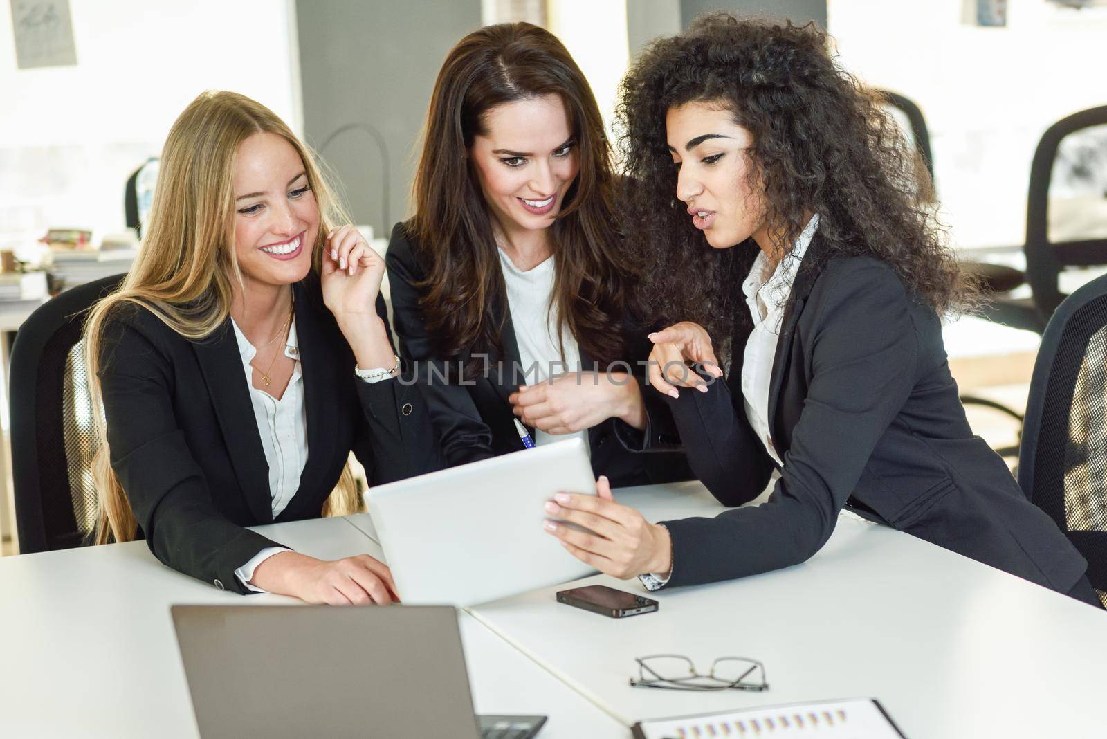Three businesswomen working together in a modern office by javiindy