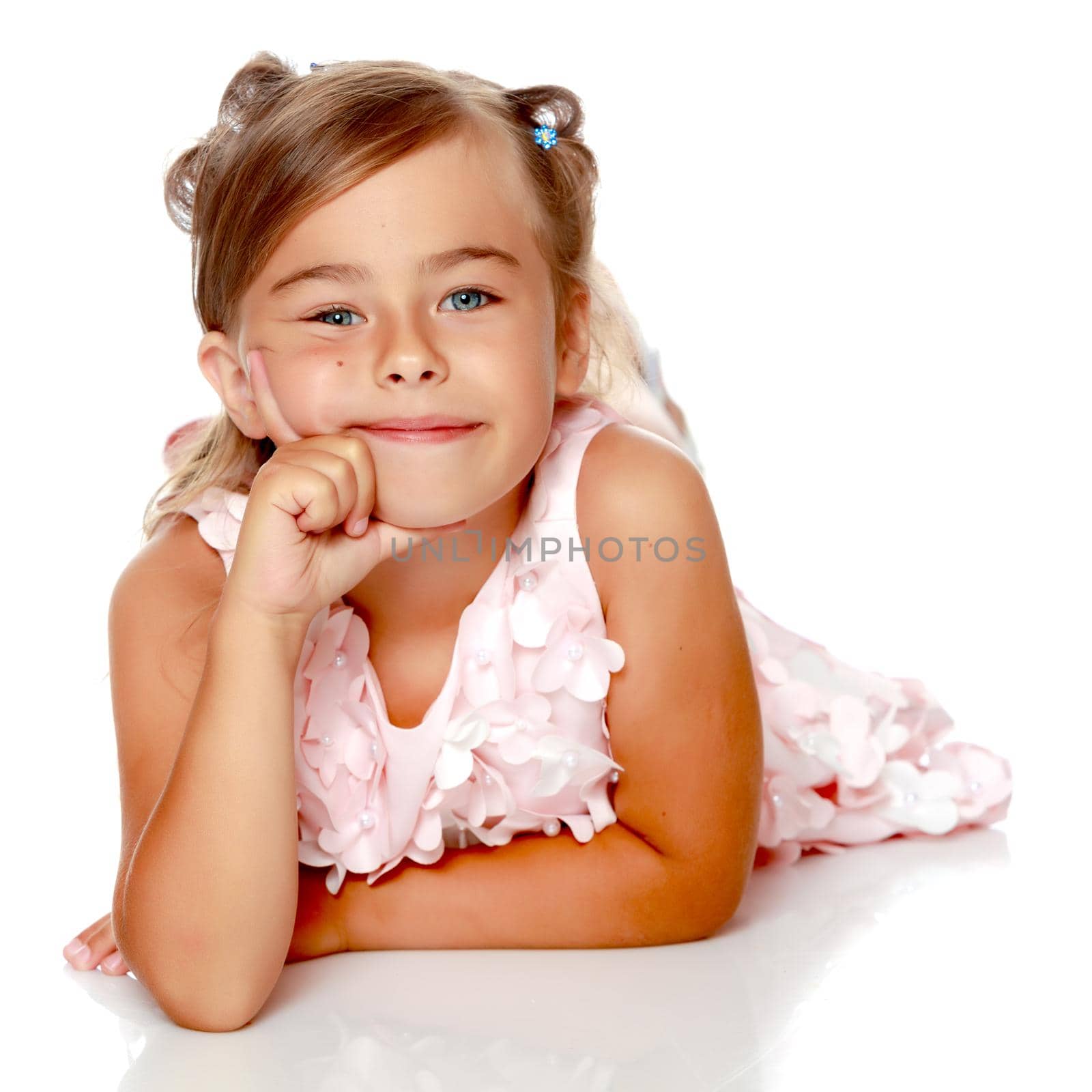 Beautiful little girl lies on the floor on a white background. The concept of a happy childhood, well-being in the family. Isolated.