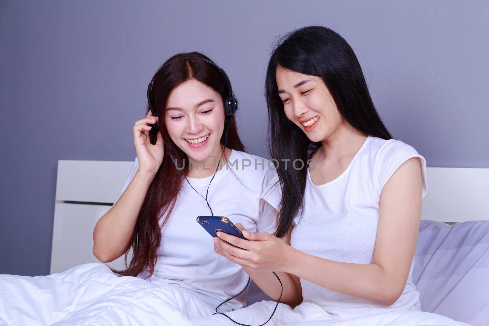 two woman using a phone in her hand on bed in bedroom by geargodz