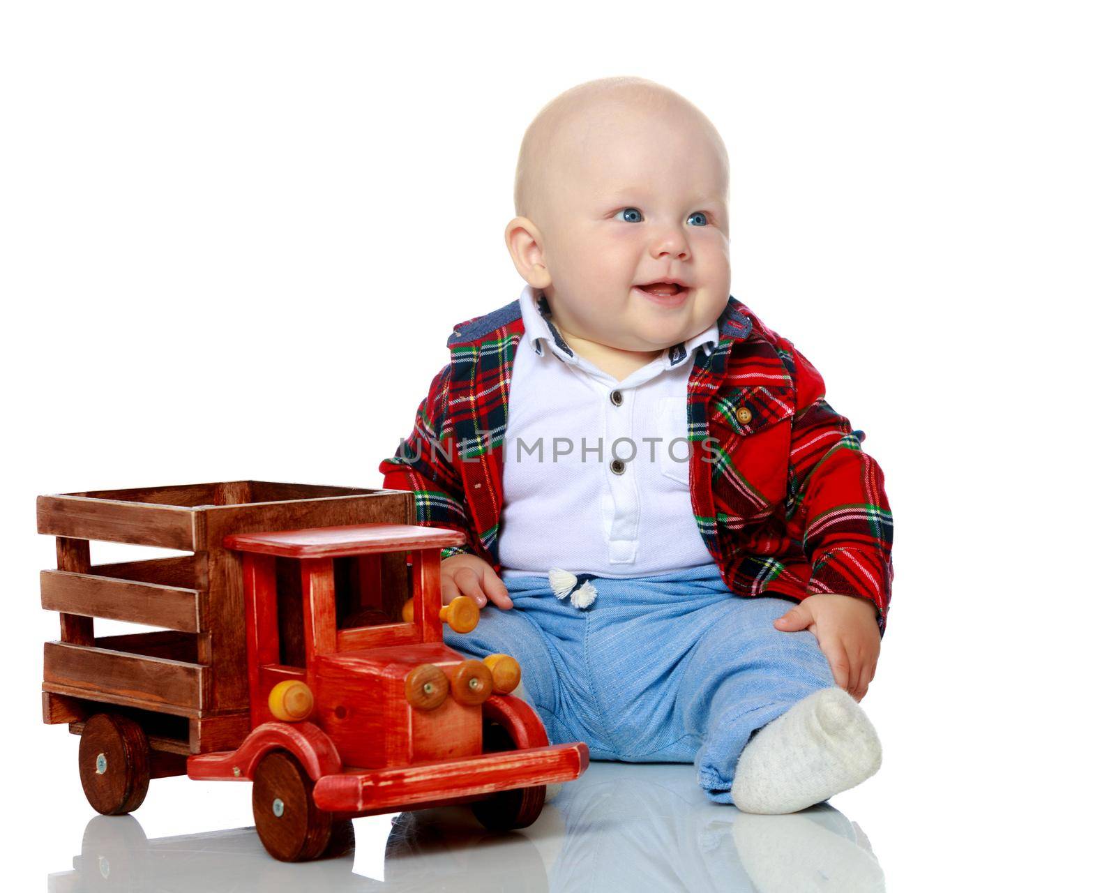 Cute little boy is playing with a toy wooden car on a white background in the studio. The concept of a happy childhood, learning and education in the family. Isolated.