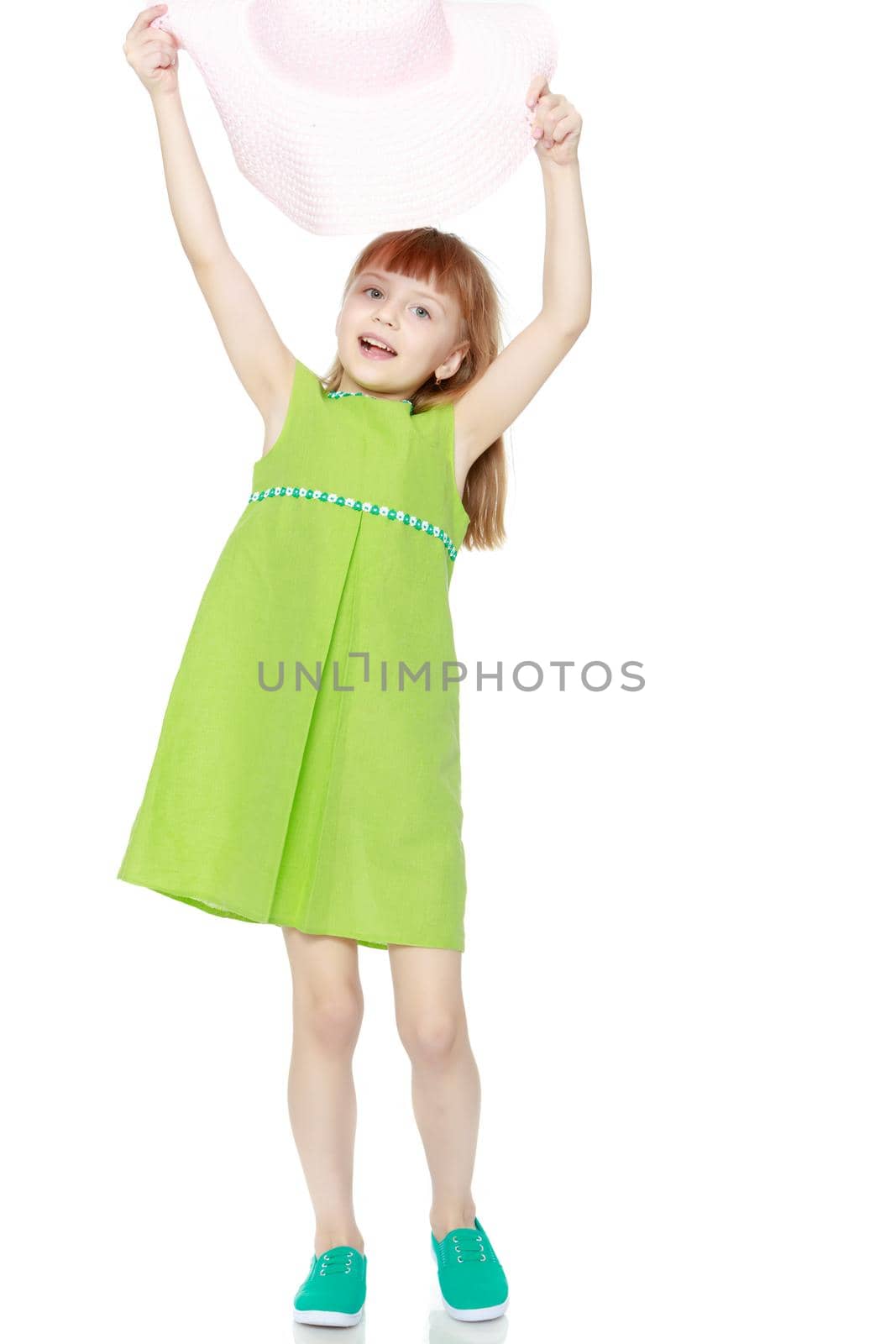 A little girl with long blond hair and a short bangs, in a short summer dress.A girl is posing in a beach straw hat.