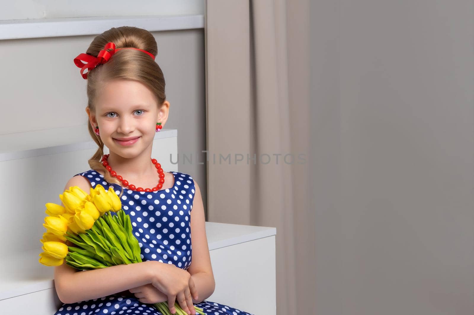 A little girl with a bouquet of tulips is sitting on the stairs. by kolesnikov_studio
