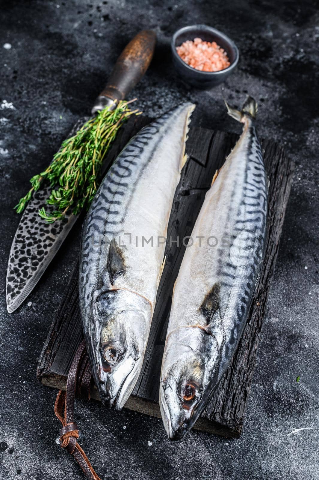 Raw fish Mackerel on a wooden cutting board. Black background. Top view.