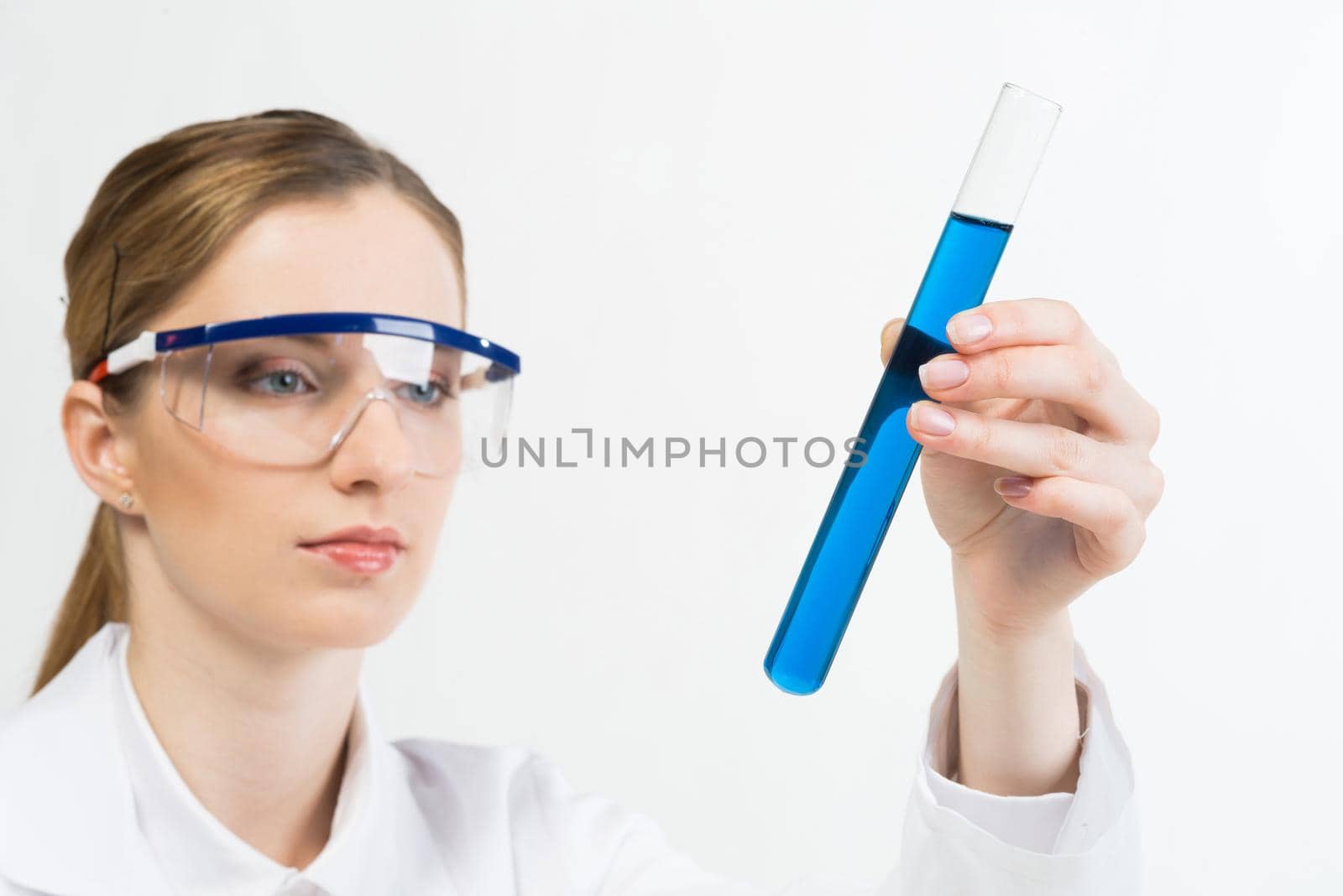 Laboratory analysis and testing. Beautiful woman scientist in protective goggles holding test tube with liquid. Pharmaceutical or chemical industry research and experimentation. Clinic lab examination