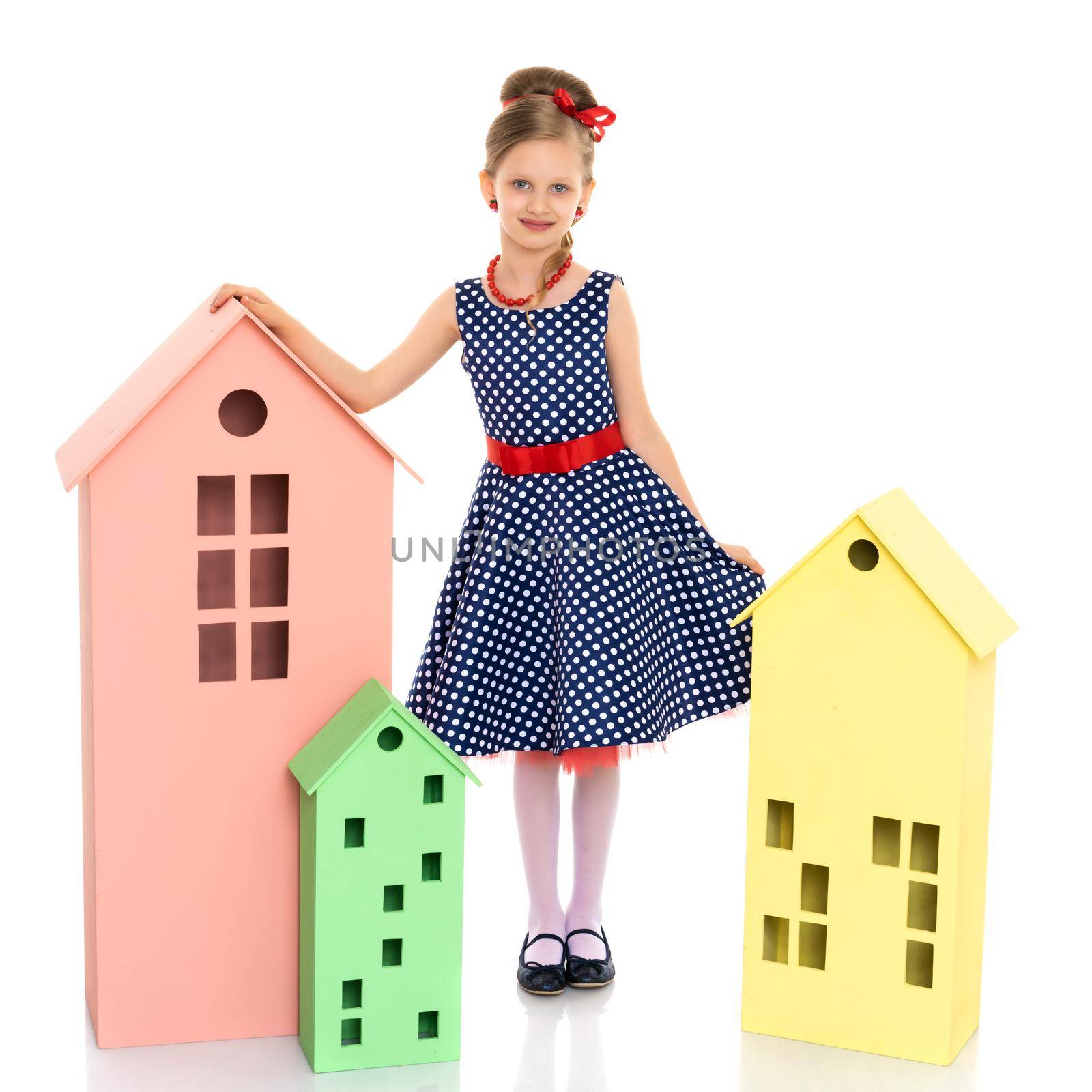 A cute little girl is playing with wooden houses. The concept of family happiness, play, creative development of the child.