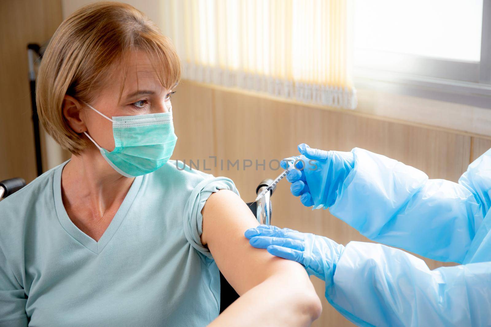 Doctor woman holding syringe and injection vaccine patient elderly in face mask for prevention coronavirus at hospital, vaccination for pandemic of senior, infection and immunization, medical concept.