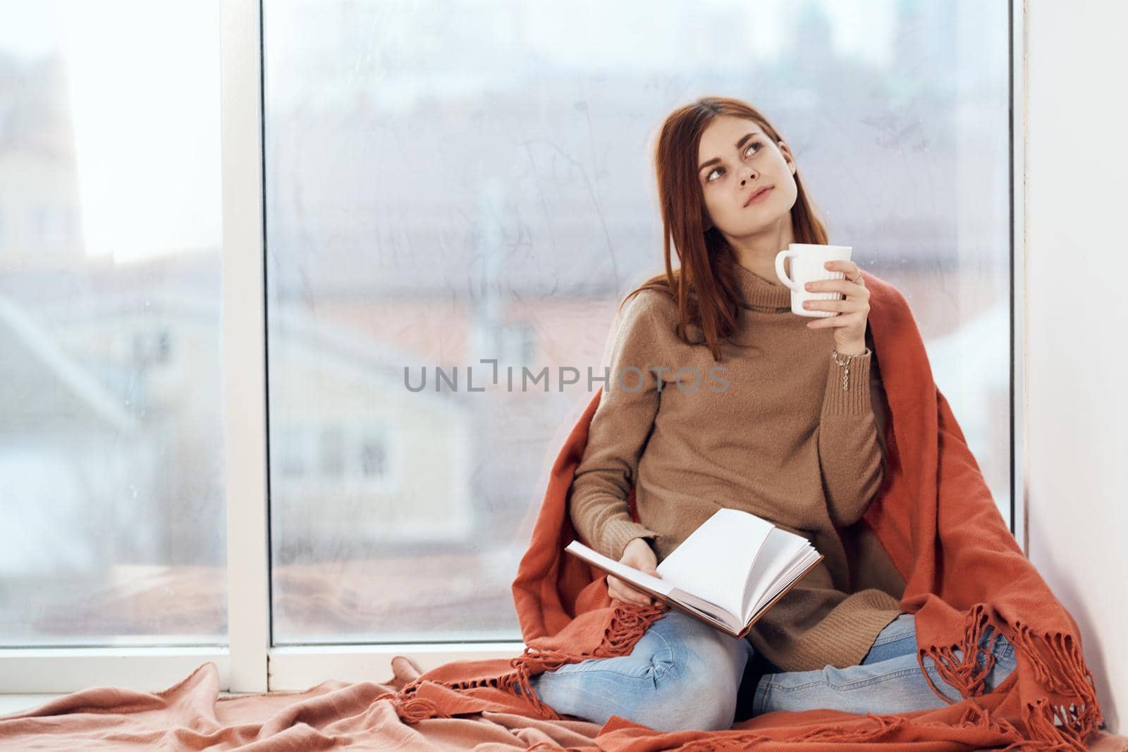 woman with a cup of drink on the windowsill reading a book rest morning. High quality photo