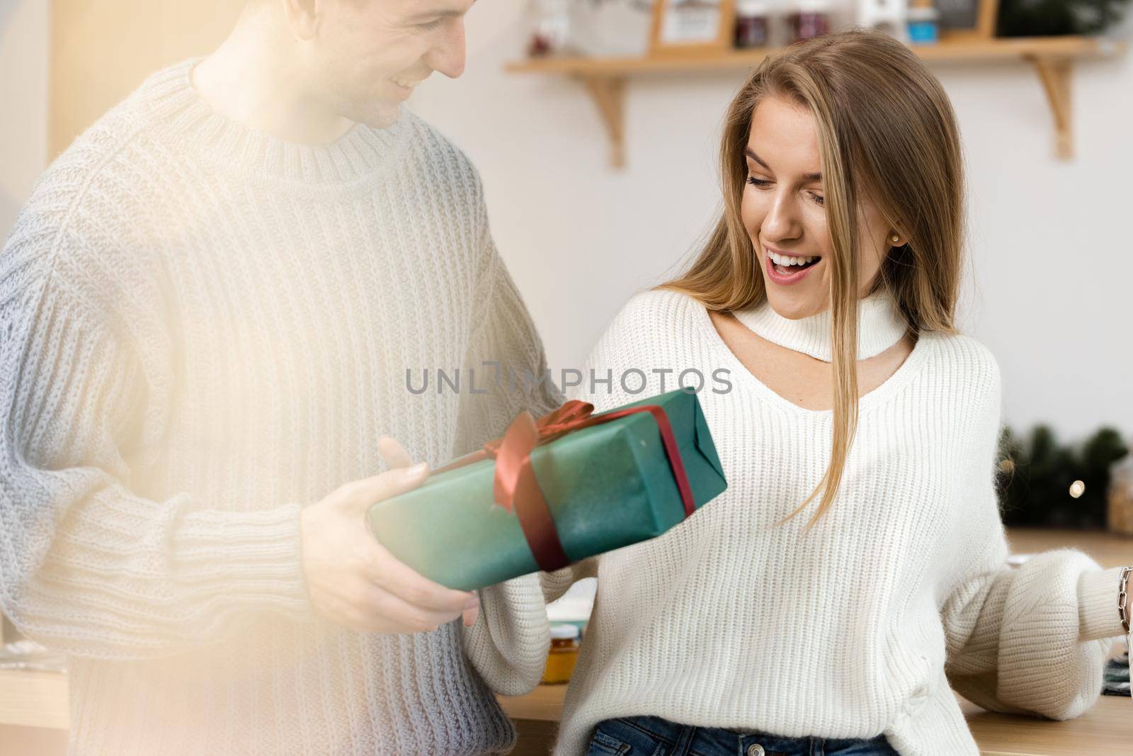 Sweet young couple opening Christmas gifts in the living room at home