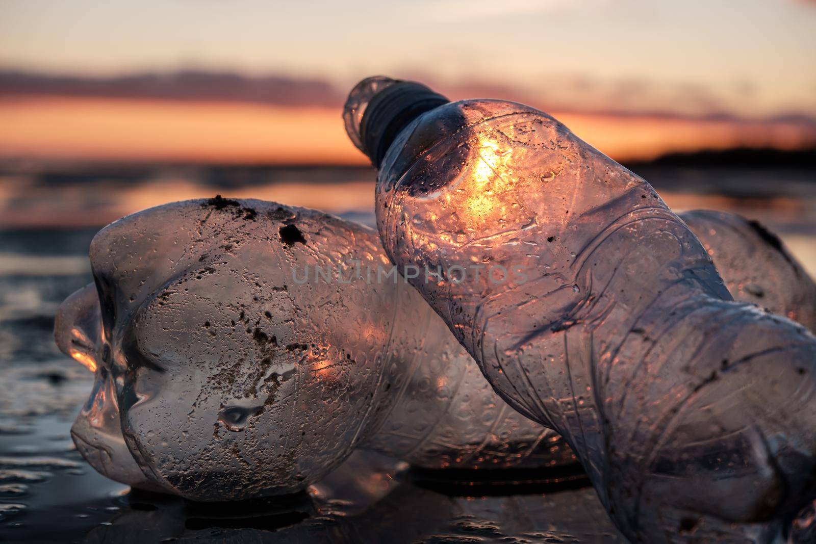 Close-up of plastic bottles thrown on the shore in the backlight by vollirikan