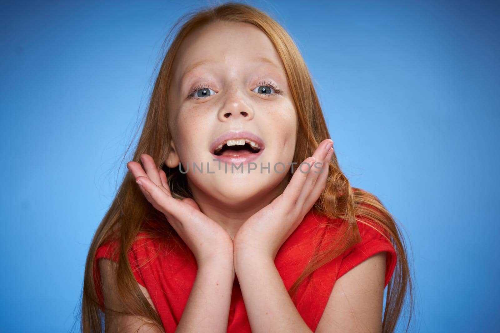 cute red-haired girl in red t-shirt emotions blue background. High quality photo