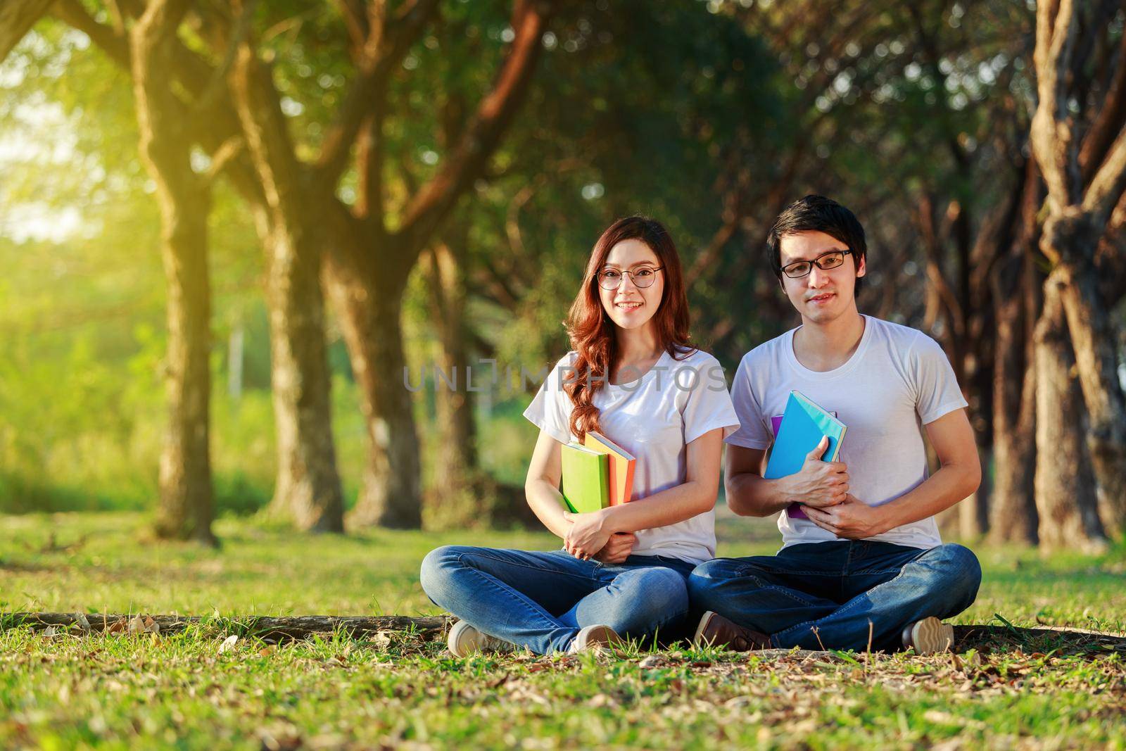 couple holding a book and resting in park by geargodz