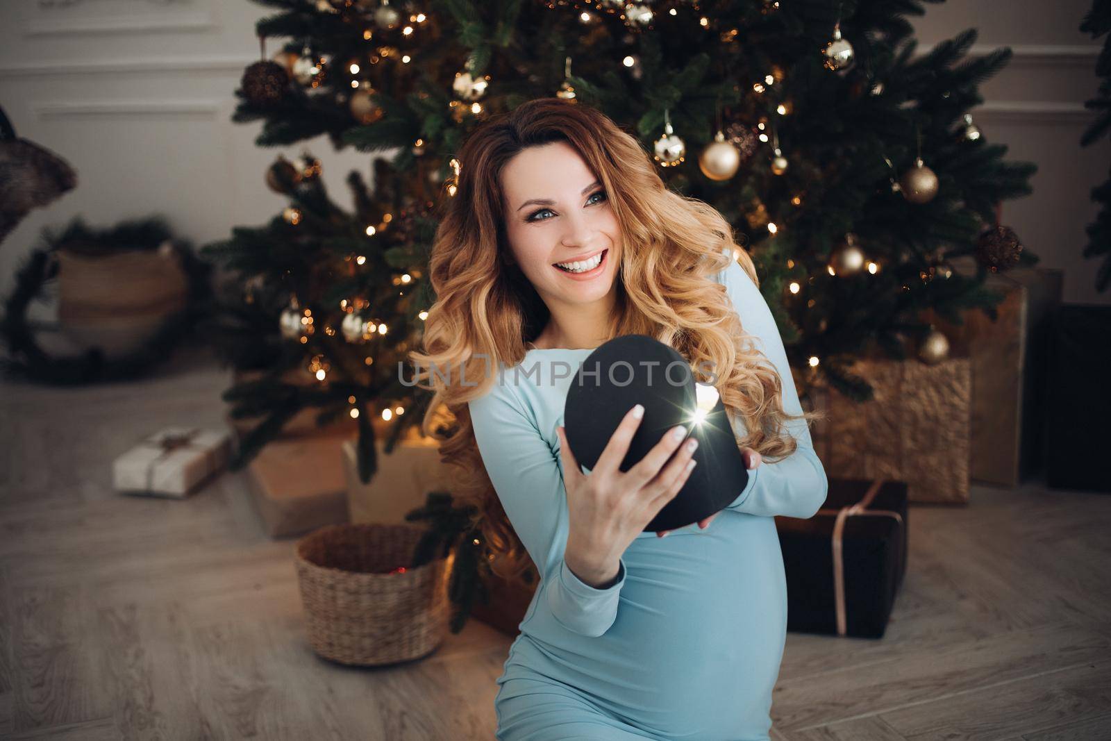 Happy pregnancy woman opening holiday light gift having positive emotion by StudioLucky