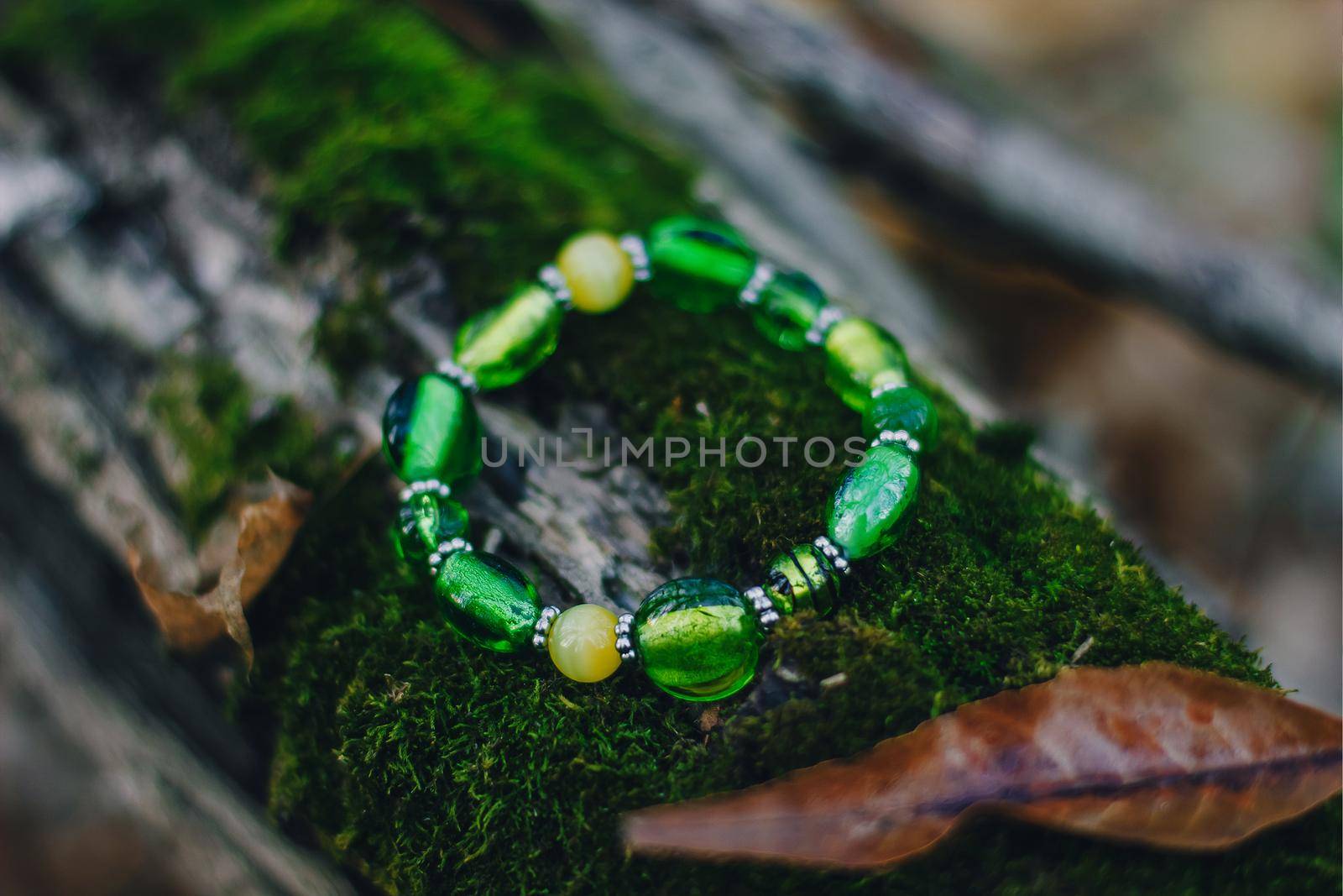Bracelet handmade handcrafted do-it-yourself glass jewelry on natural wood forest background. Business idea, earning money for a hobby. Useful quarantined skills by mmp1206