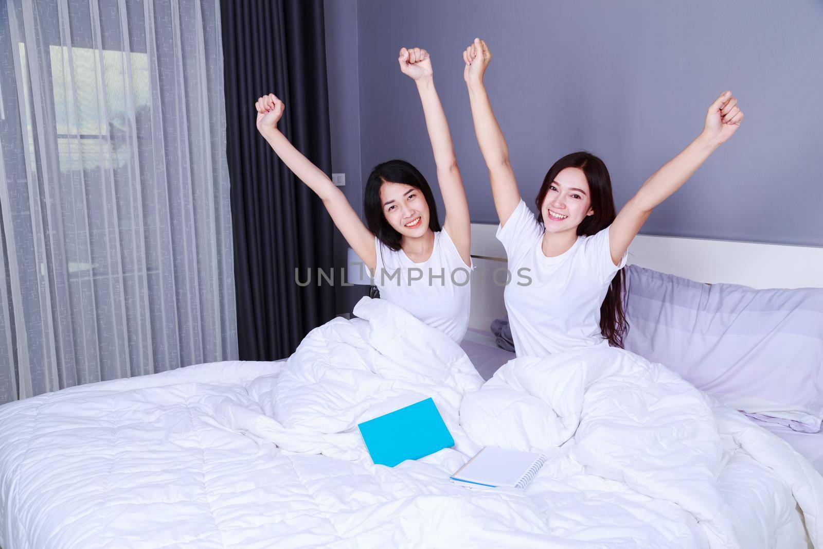 best friend woman with arms raised on bed in the bedroom