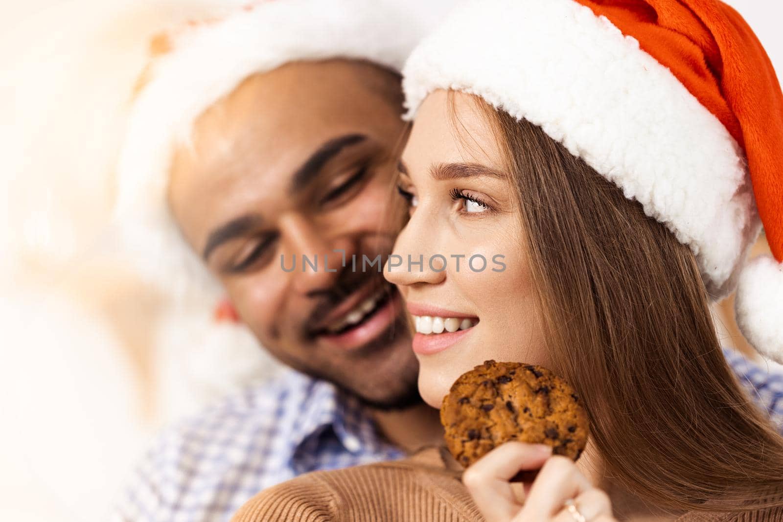 Cheerful attractive happy couple in Santa hats, close up portrait