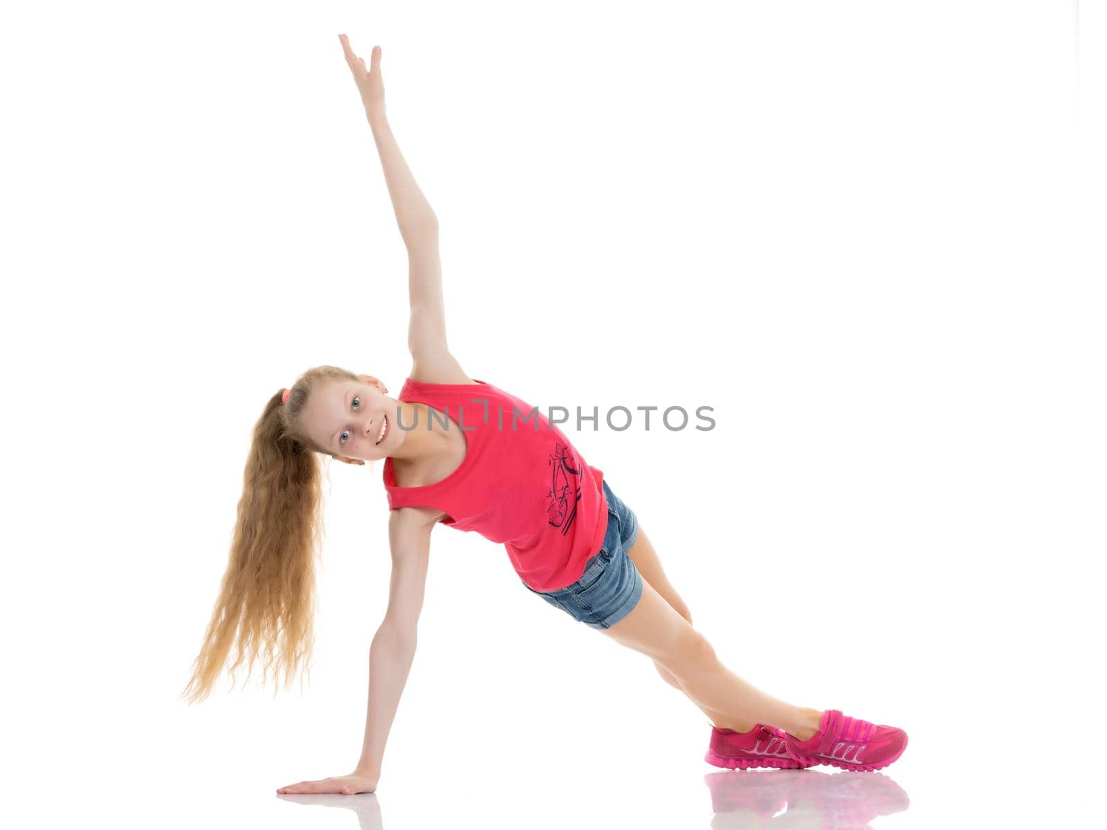 A girl gymnast performs an acrobatic element on the floor. The concept of childhood, sport, healthy lifestyle. Isolated on white background.