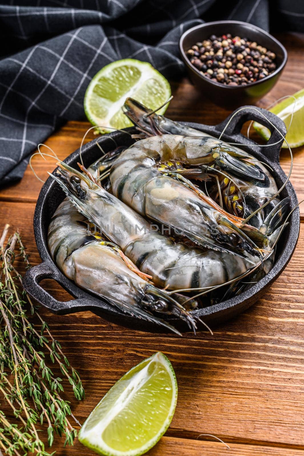 Fresh tiger shrimps, prawns with spices and herbs in a pan. wooden background. Top view.