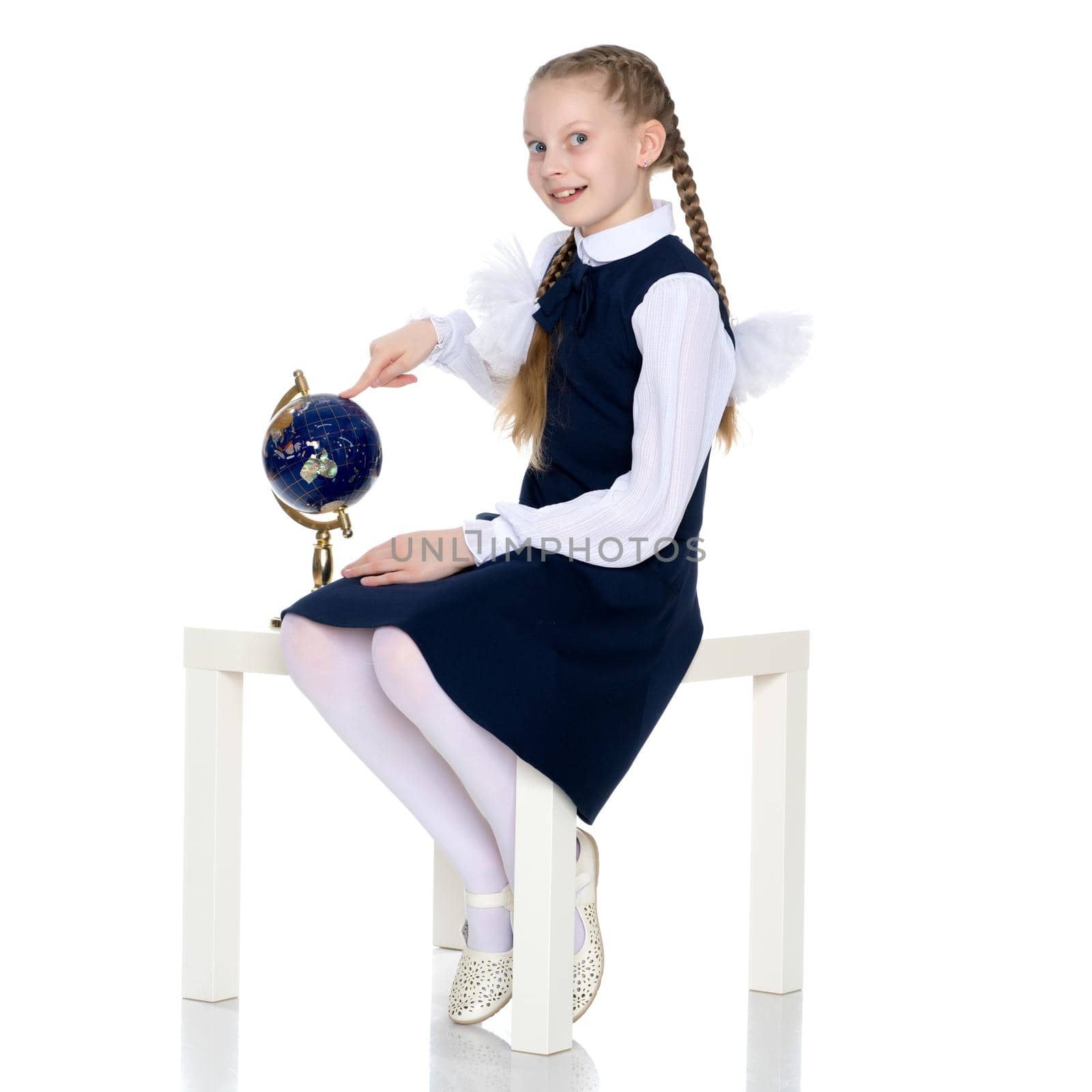 Beautiful little schoolgirl girl studying a globe on a white background. The concept of teaching geography in school, travel. Isolated.