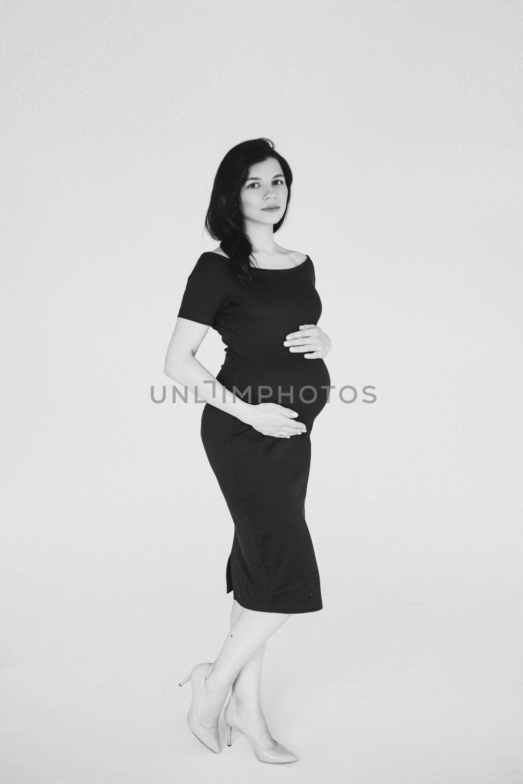 cheerful pregnant caucasian womaan waiting her baby and touching her tummy, black and white picture isolated on white background