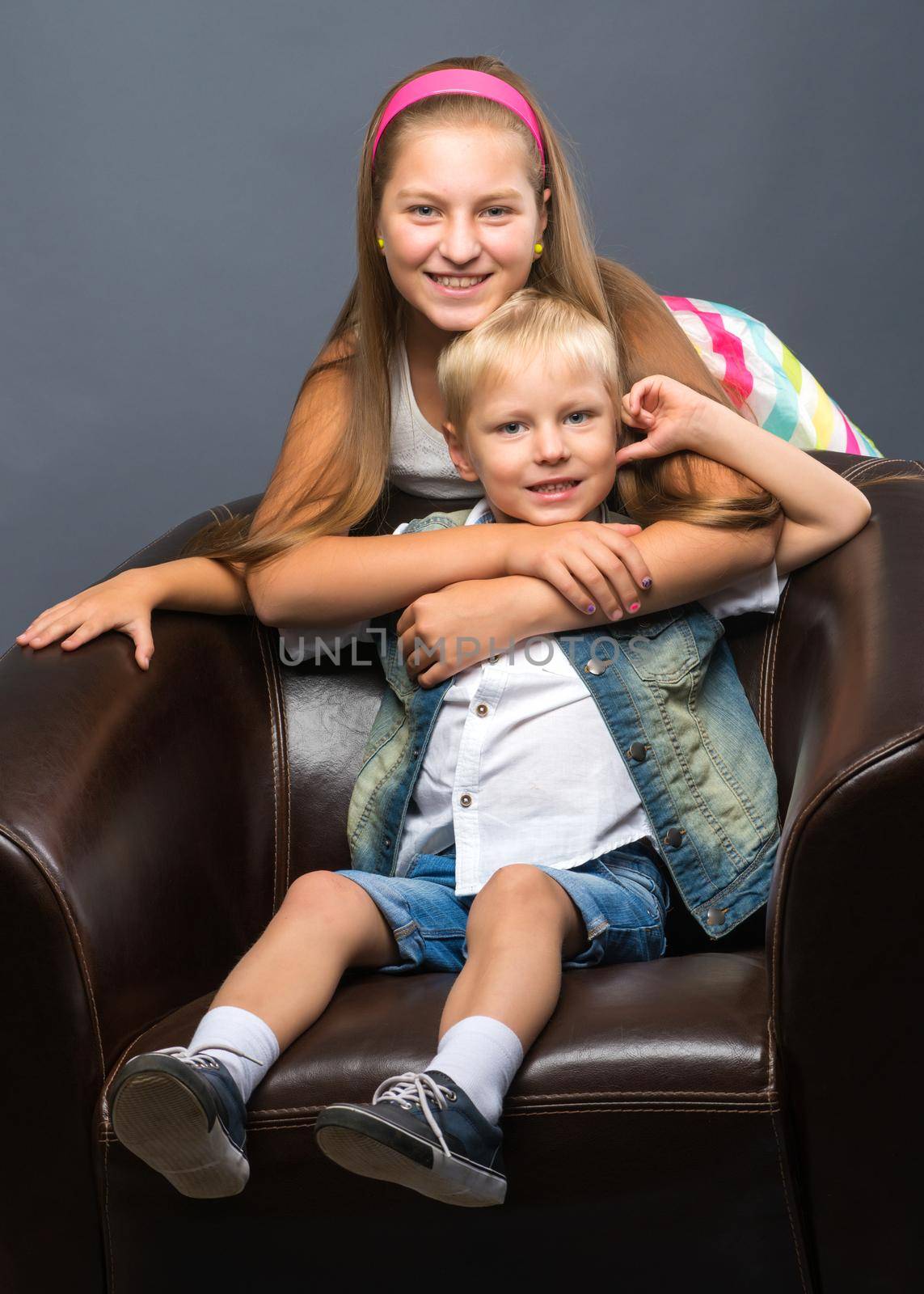 A teenage girl with her younger brother. studio photo session. The concept of family happiness.