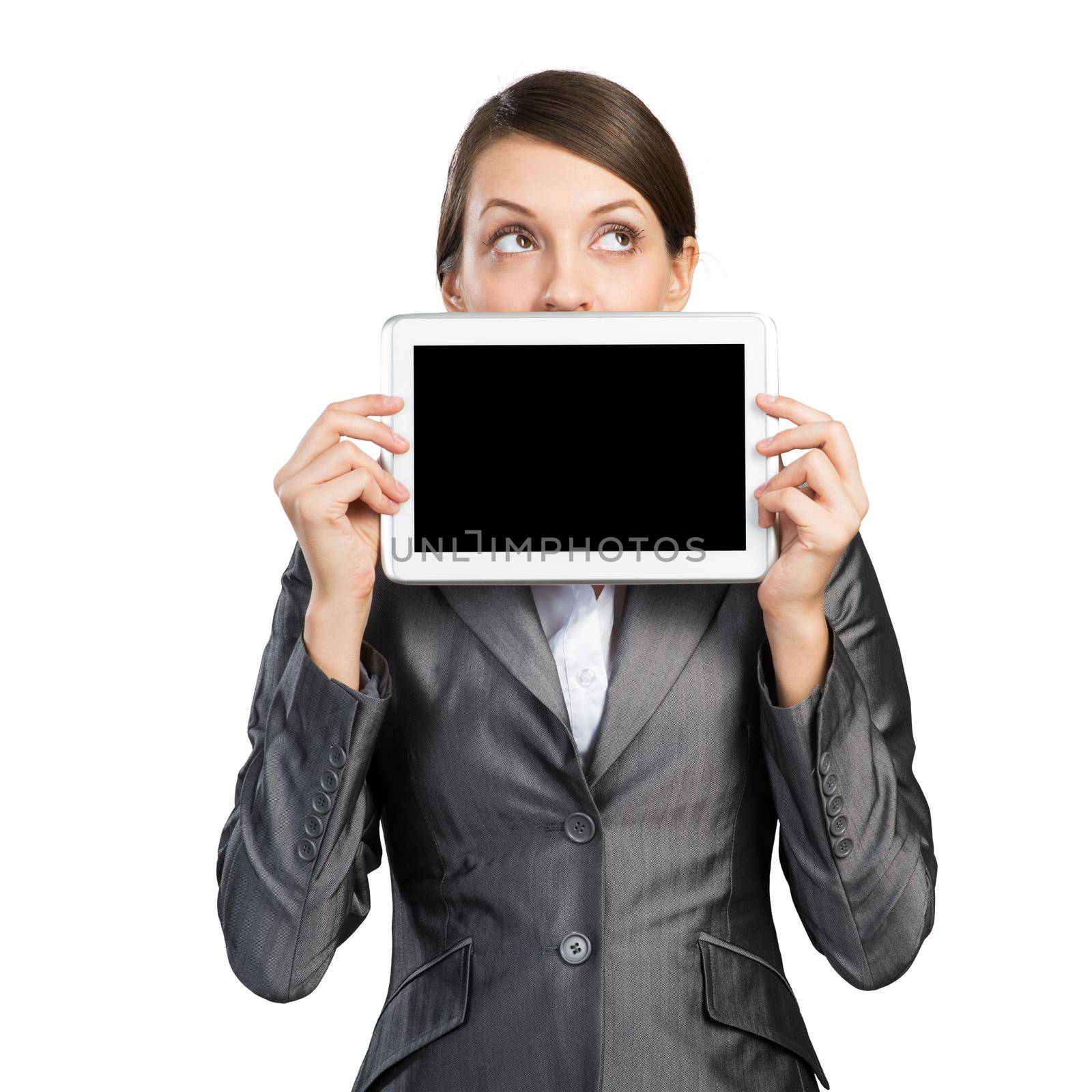 Businesswoman with tablet computer looking upwards. Portrait of attractive woman in formalwear showing tablet PC near her face. Corporate businessperson and digital technology layout with copy space
