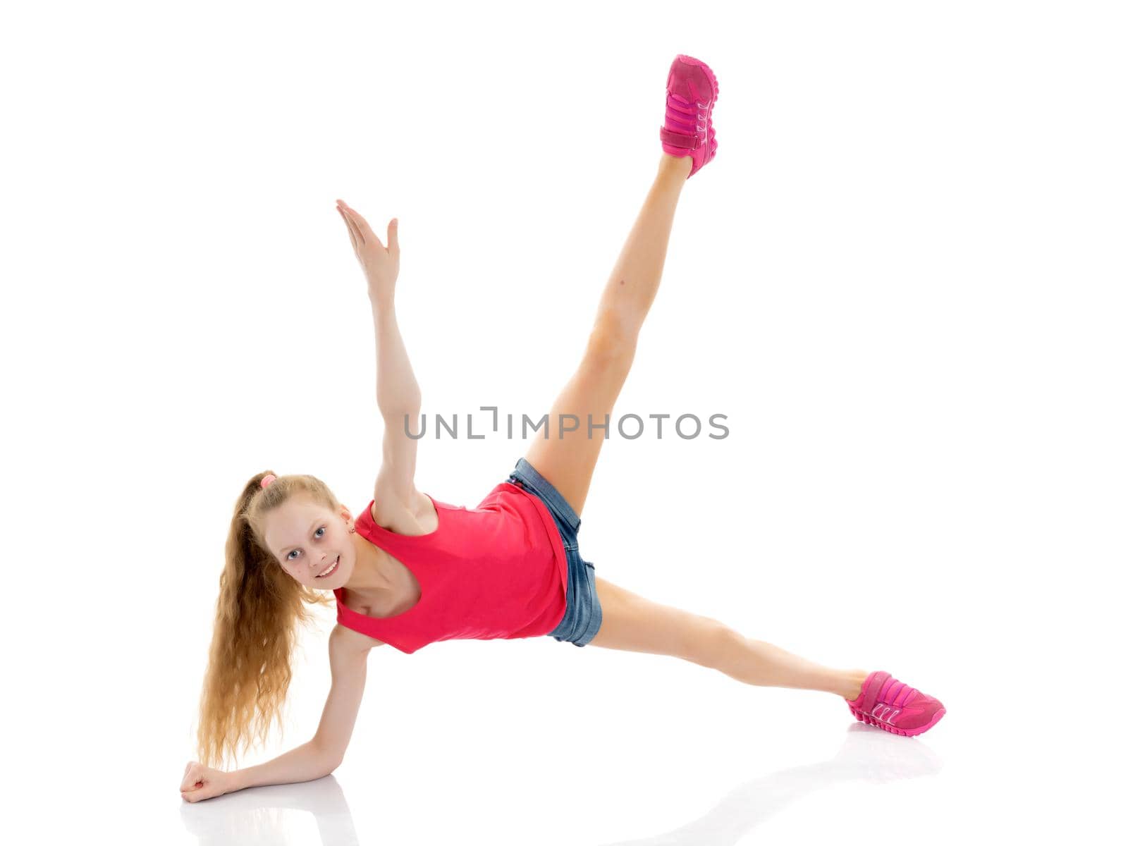 A girl gymnast performs an acrobatic element on the floor. The concept of childhood, sport, healthy lifestyle. Isolated on white background.