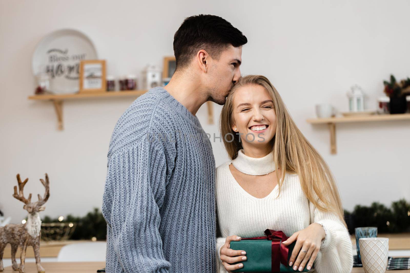 Sweet young couple opening Christmas gifts in the living room at home