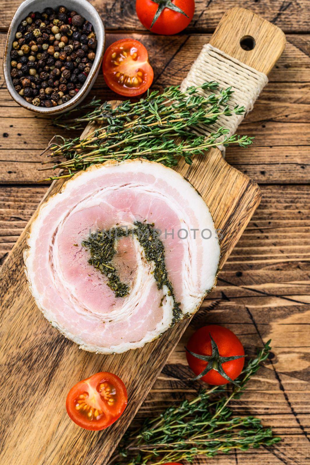 Pancetta, typical italian roll raw bacon. Wooden background. Top view.