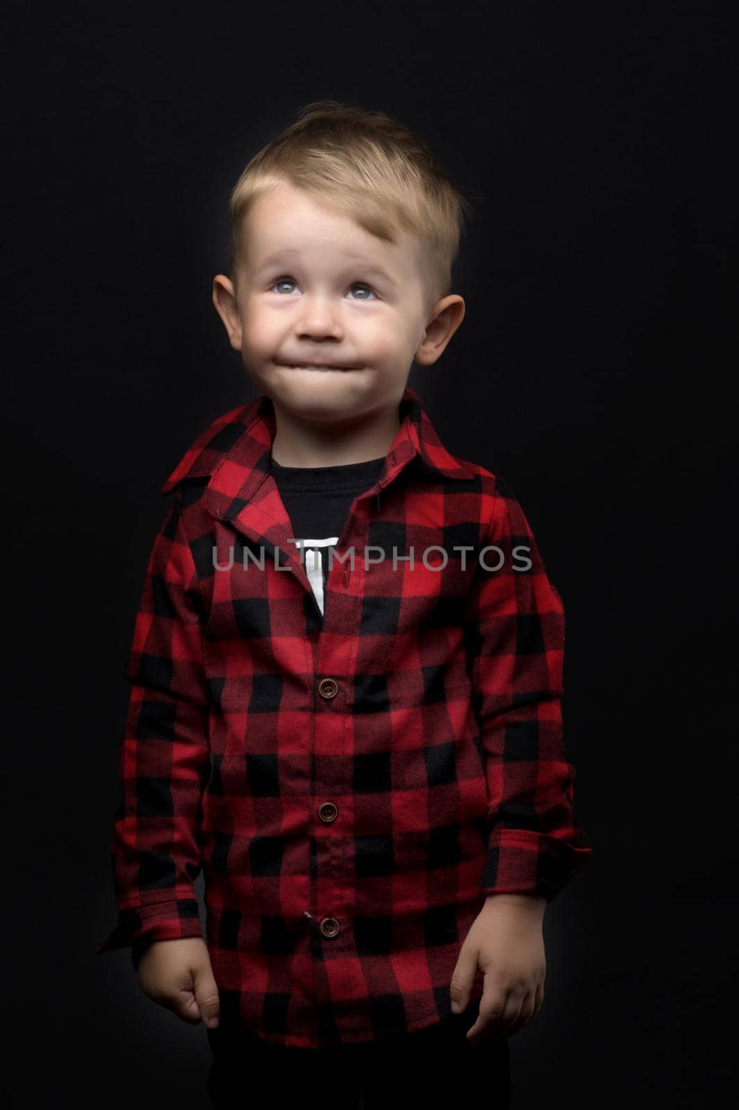 Cute little boy in studio on a black background. Concept Happy childhood, beauty and people.