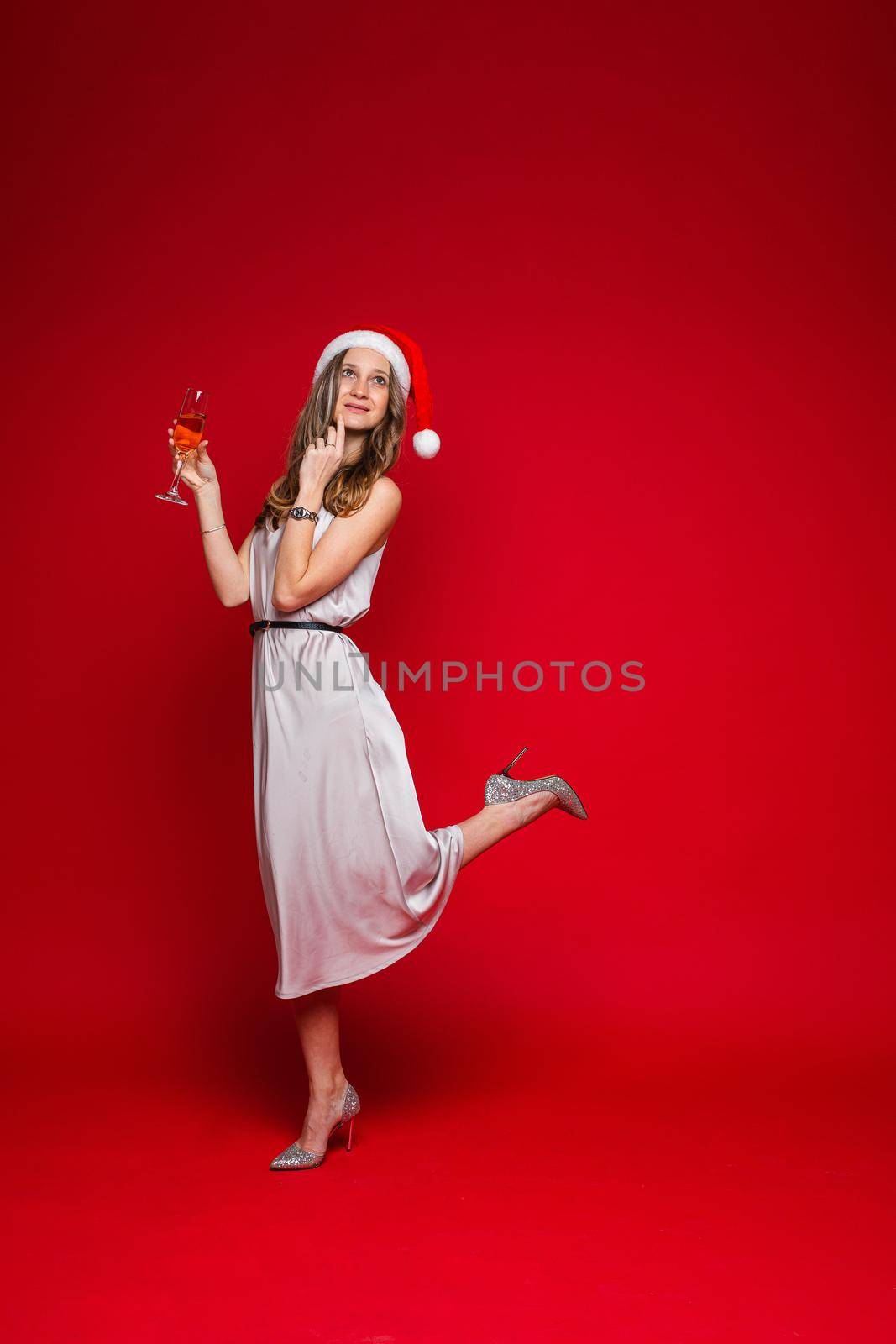 caucasian woman with attractive appearance holds a glass of white wine, picture isolated on red background