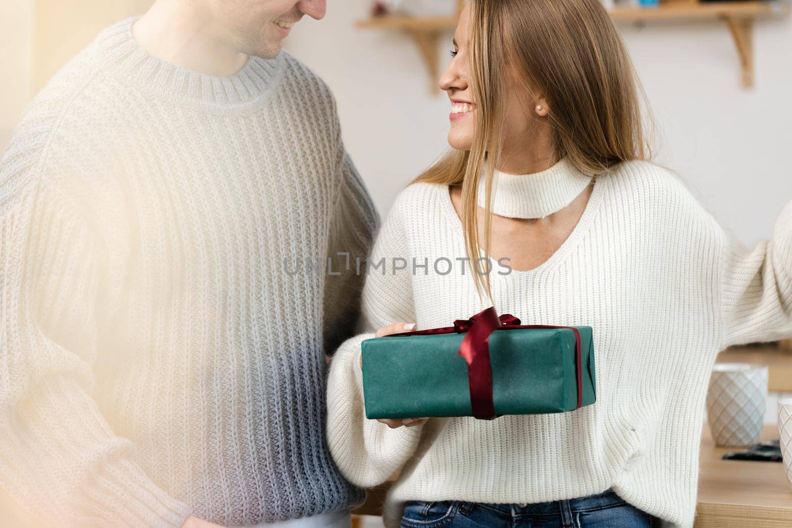 Sweet young couple opening Christmas gifts in the living room at home