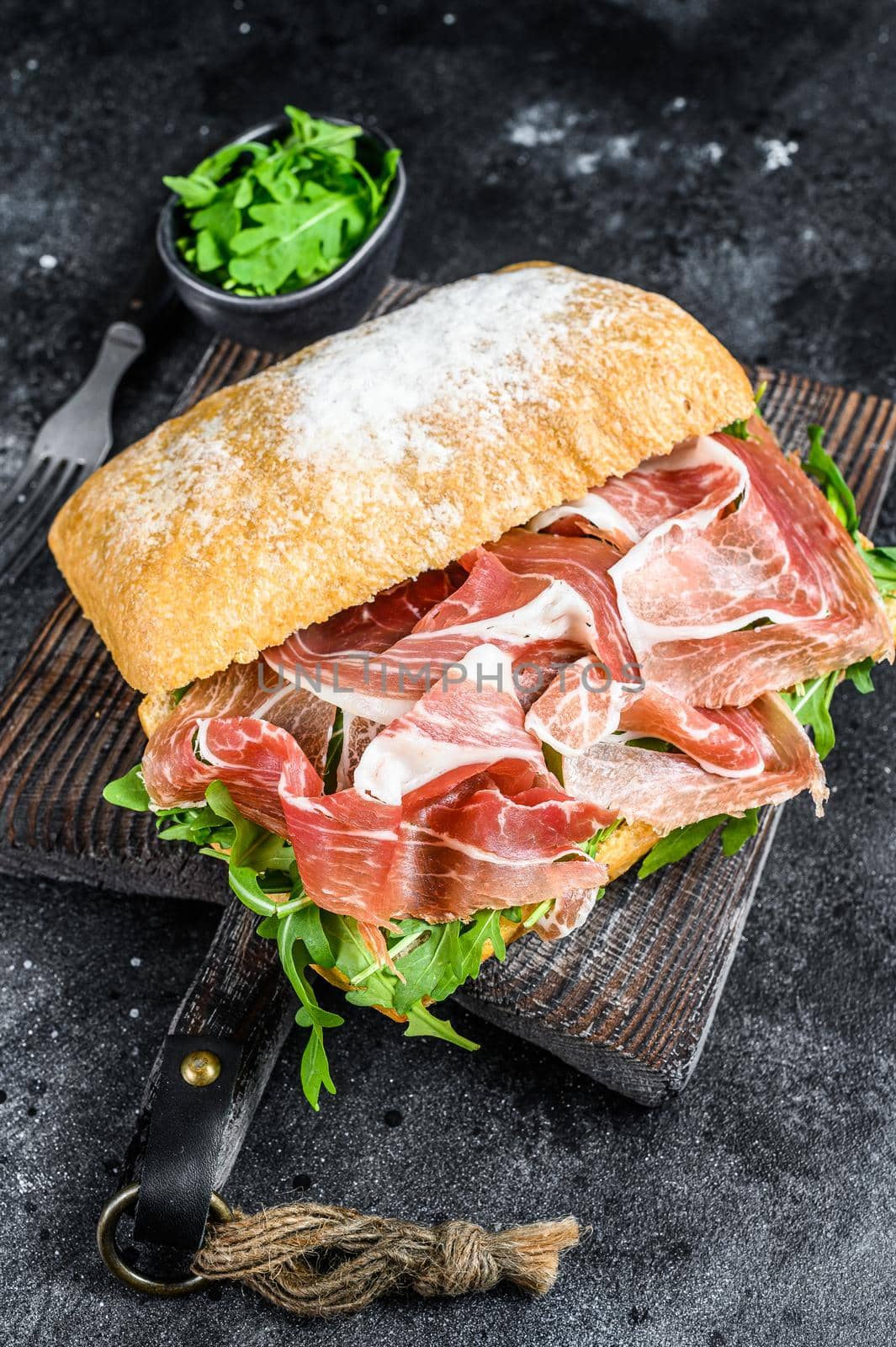 iberico jamon ham sandwich on ciabatta bread. Black background. Top view.