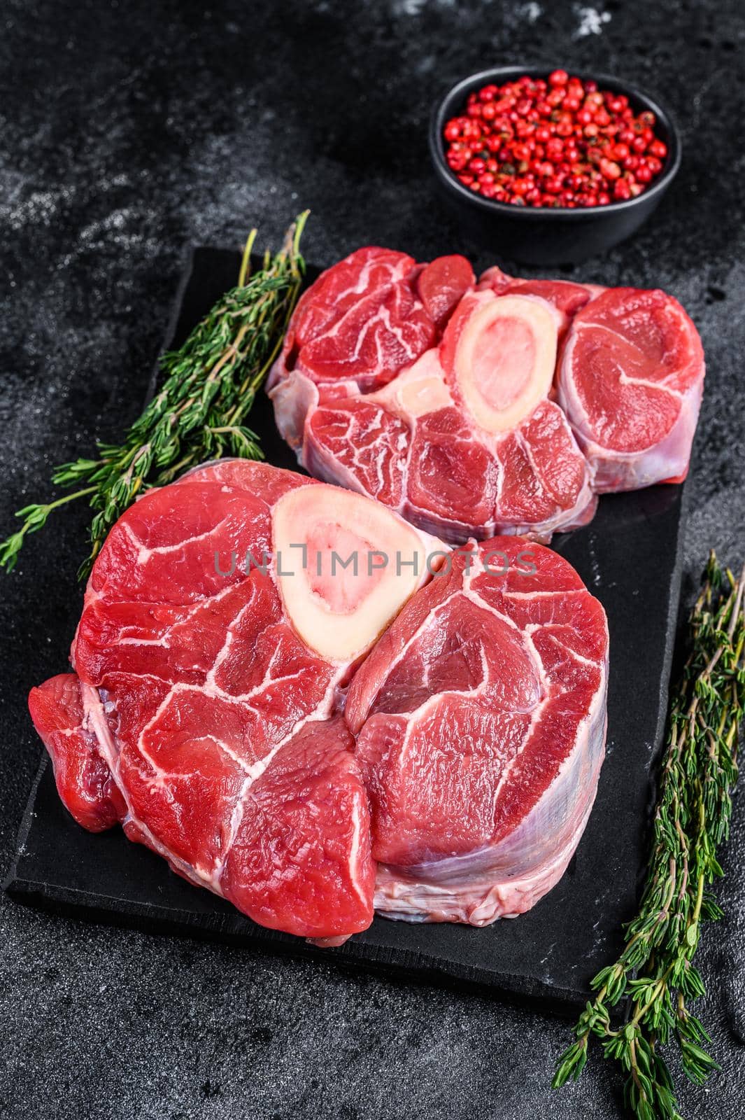 Raw beef meat osso buco shank steak, italian ossobuco. Black background. Top view.