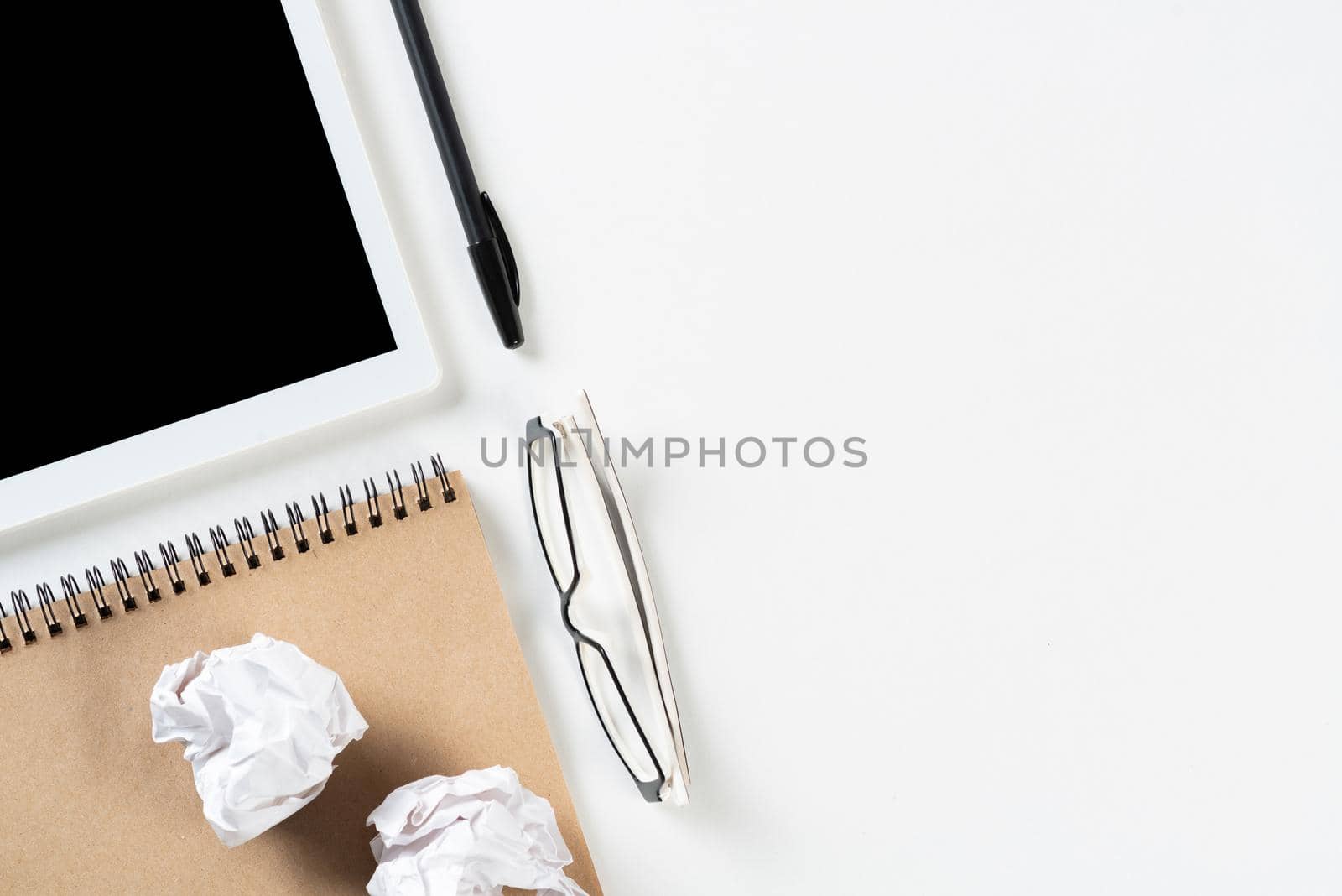 Top view of well organized home office workplace. Spiral notepad, pen and tablet computer on white surface. Education, creativity and working concept with copy space. Digital gadgets in business.