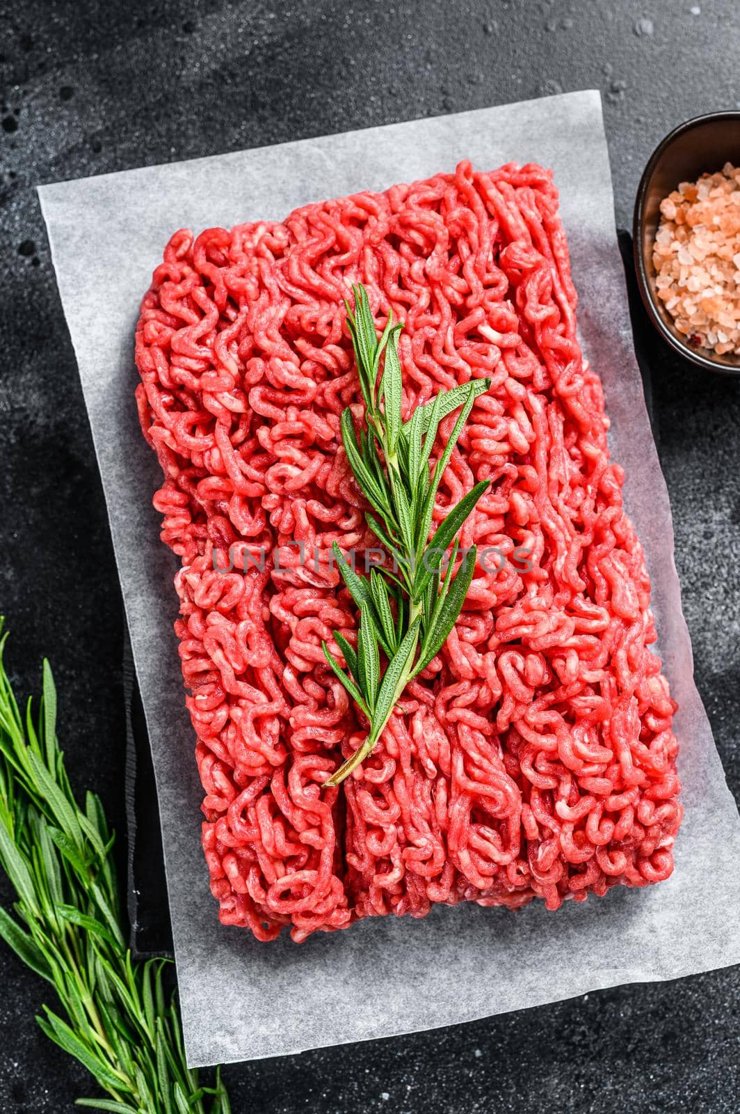 Fresh Raw mince beef, ground meat on butcher paper. Black background. Top view.