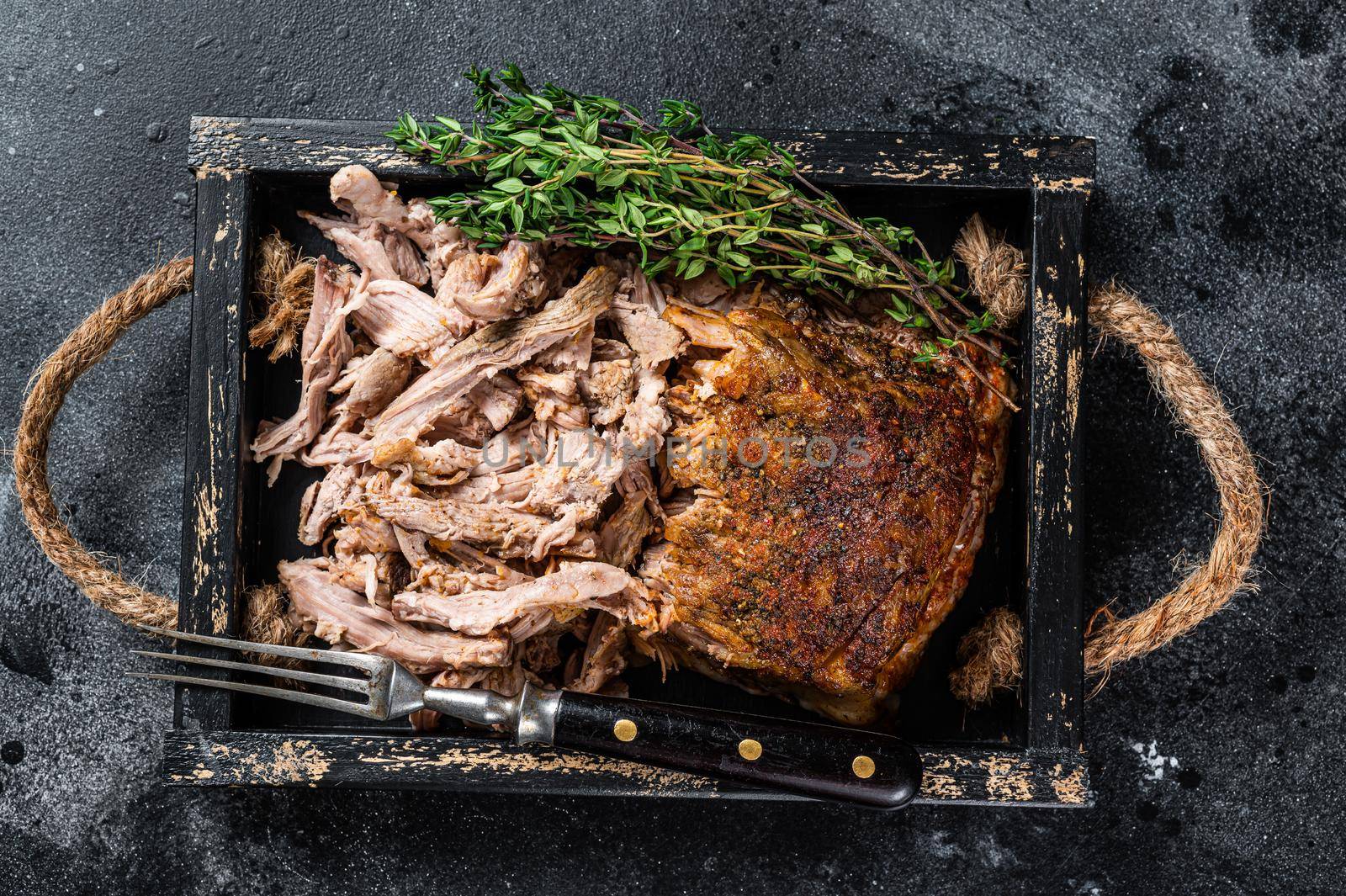 Bbq slow roast puilled pork meat in a wooden tray. Black background. Top view.