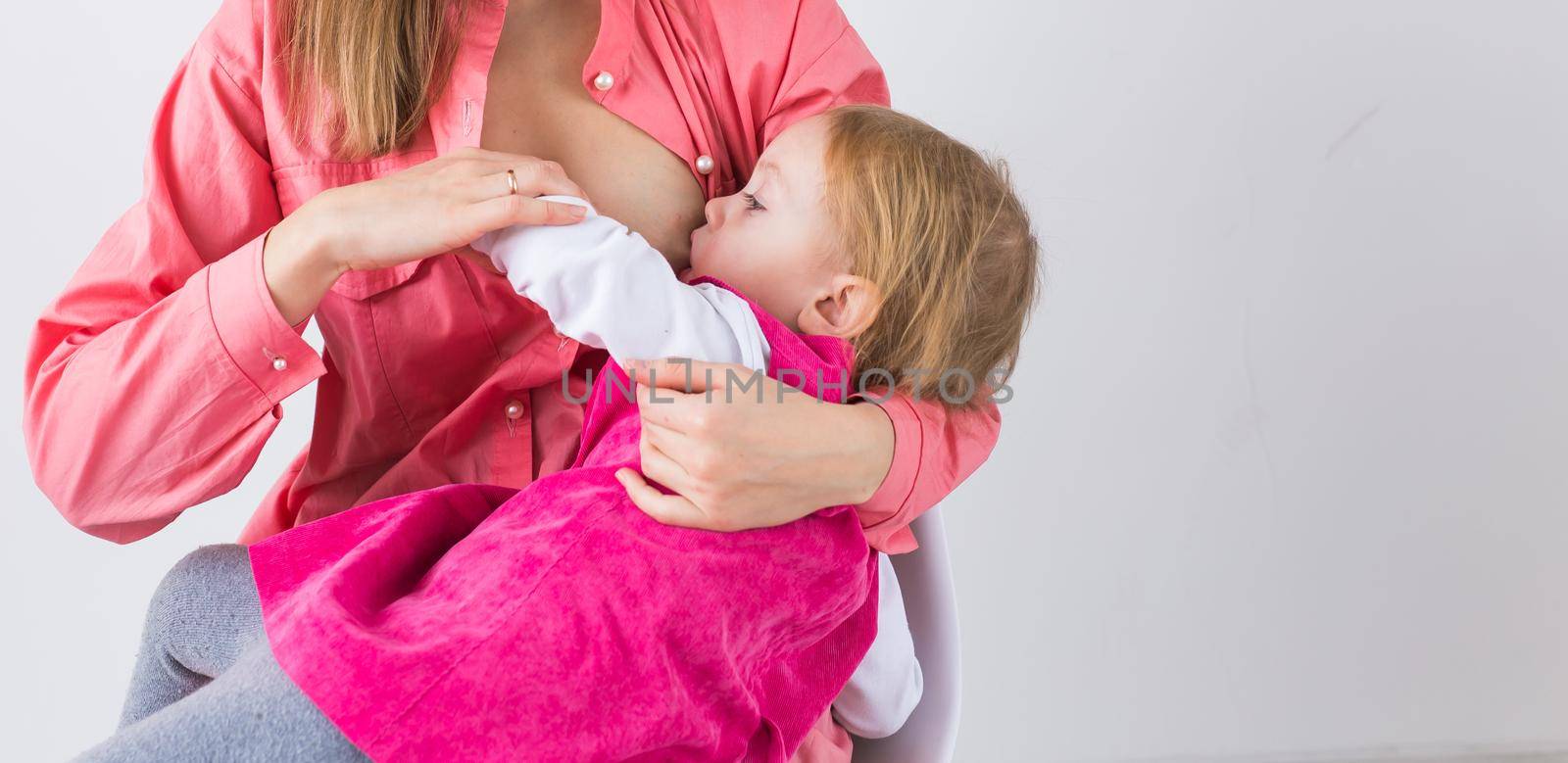 Mother breastfeeding baby in her arms at home. Child eating mother's milk. Young woman nursing and feeding baby. Concept of lactation infant. by Satura86