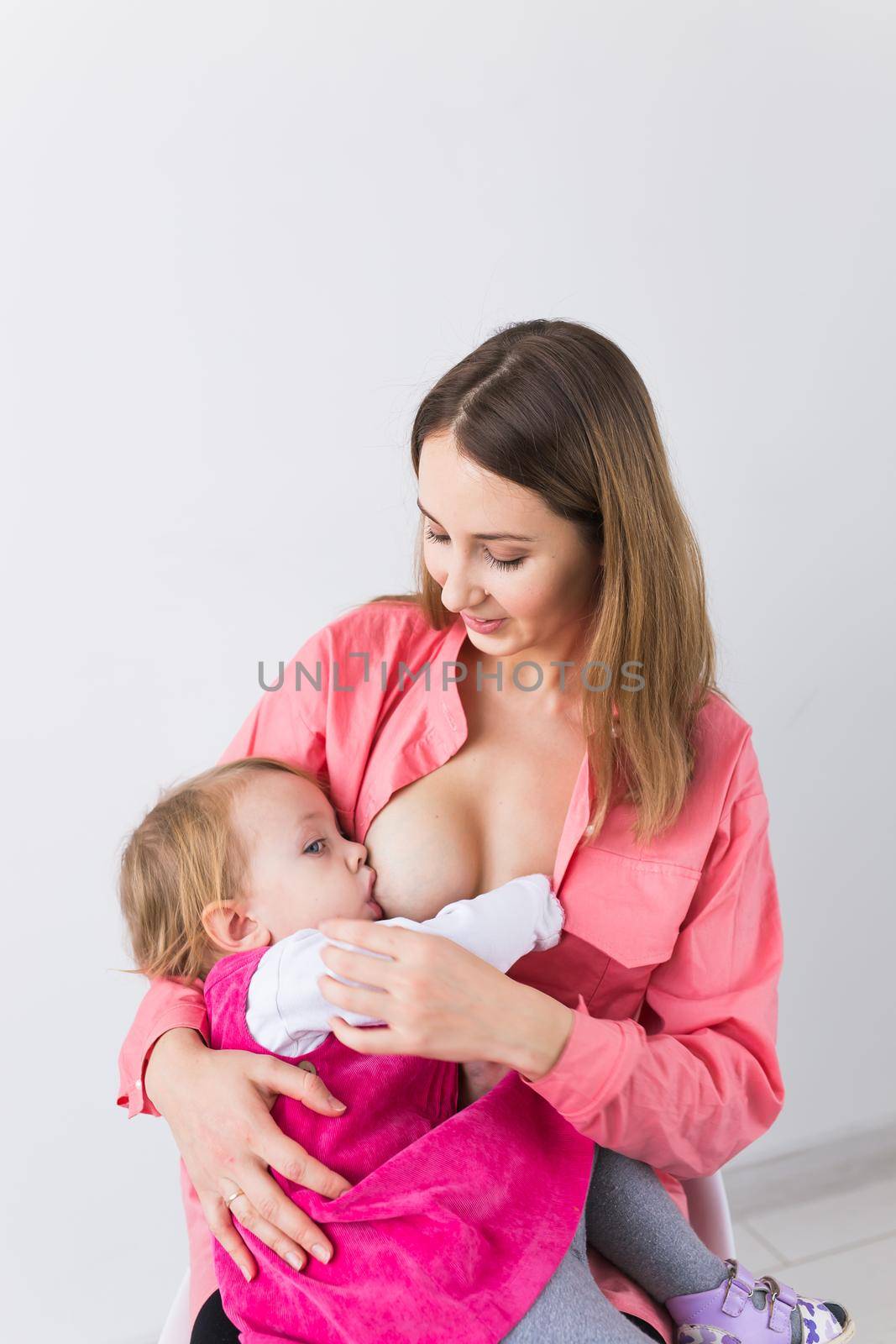 Young beautiful mother, breastfeeding her baby girl. Mom breastfeeding infant.