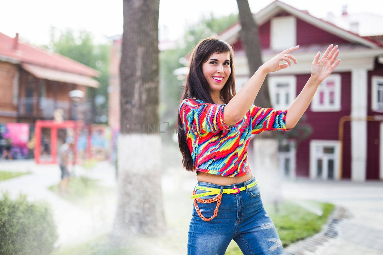 Beautiful attractive young woman having fun and enjoying and dancing in the park on a sunny summer day