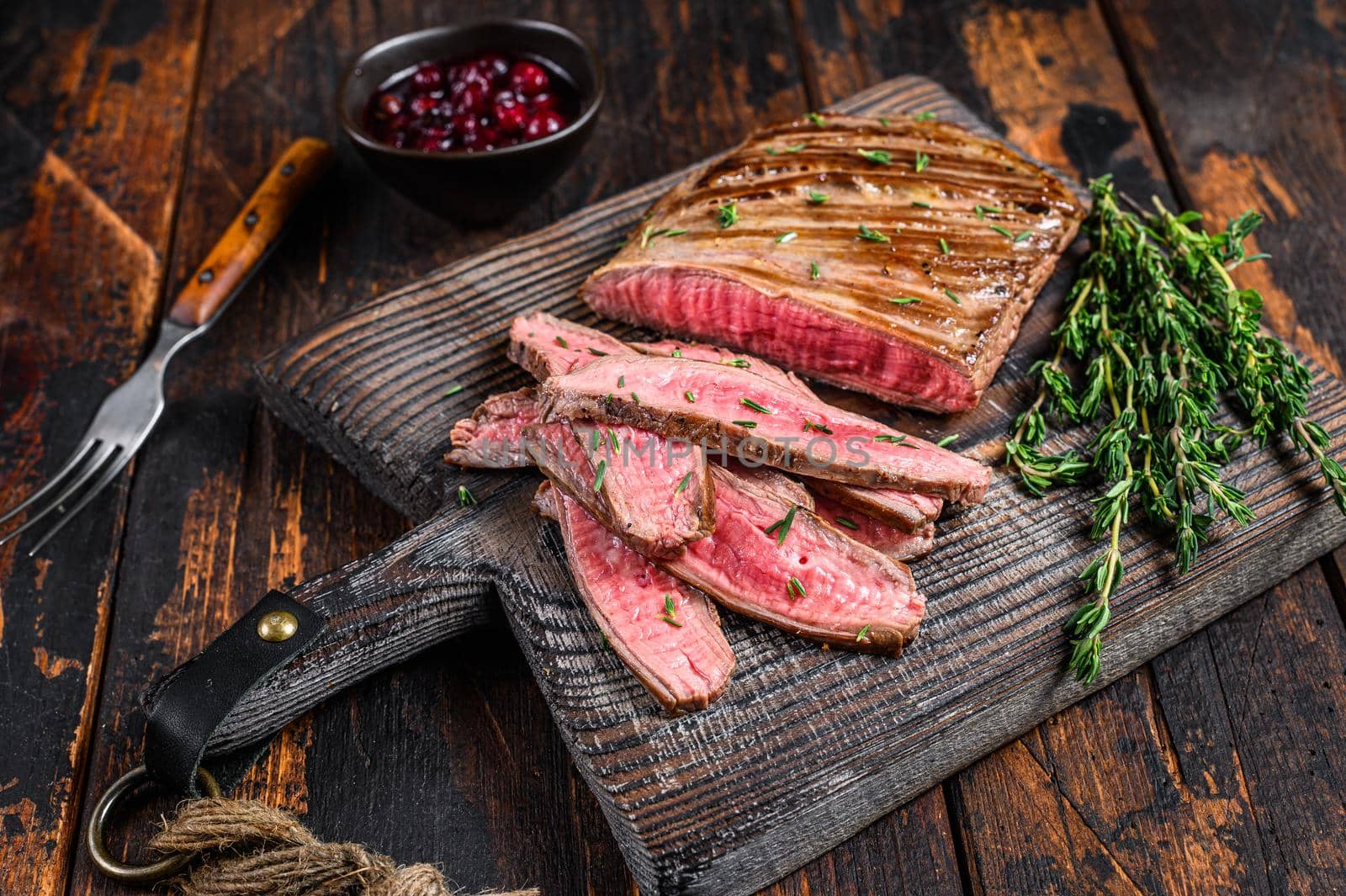 BBQ sliced skirt beef meat steak on a wooden cutting board. Dark wooden background. Top view.