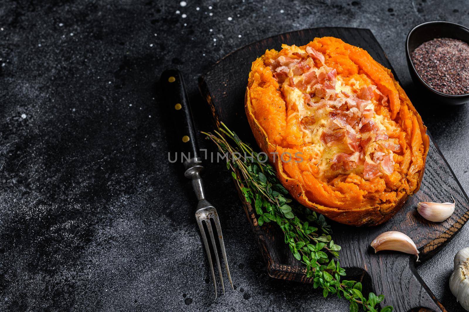 Baked sweet potato yam stuffed with ground beef and cheese. Black background. Top view. Copy space.