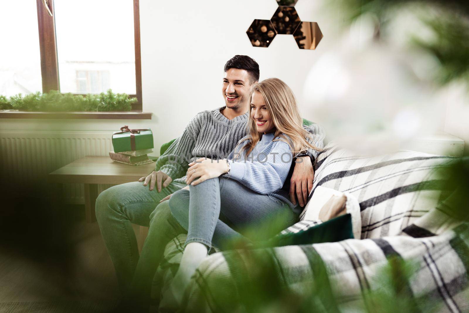 Sweet couple embracing on sofa at home during christmas holidays