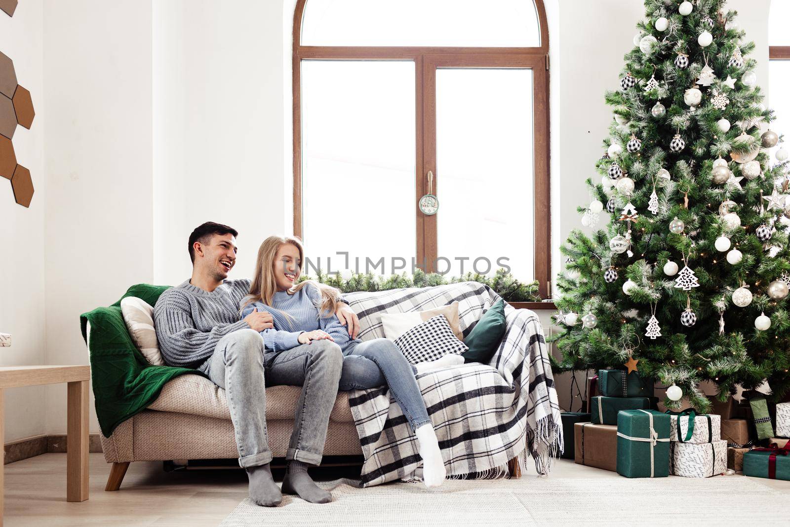 Sweet couple embracing on sofa at home during christmas holidays