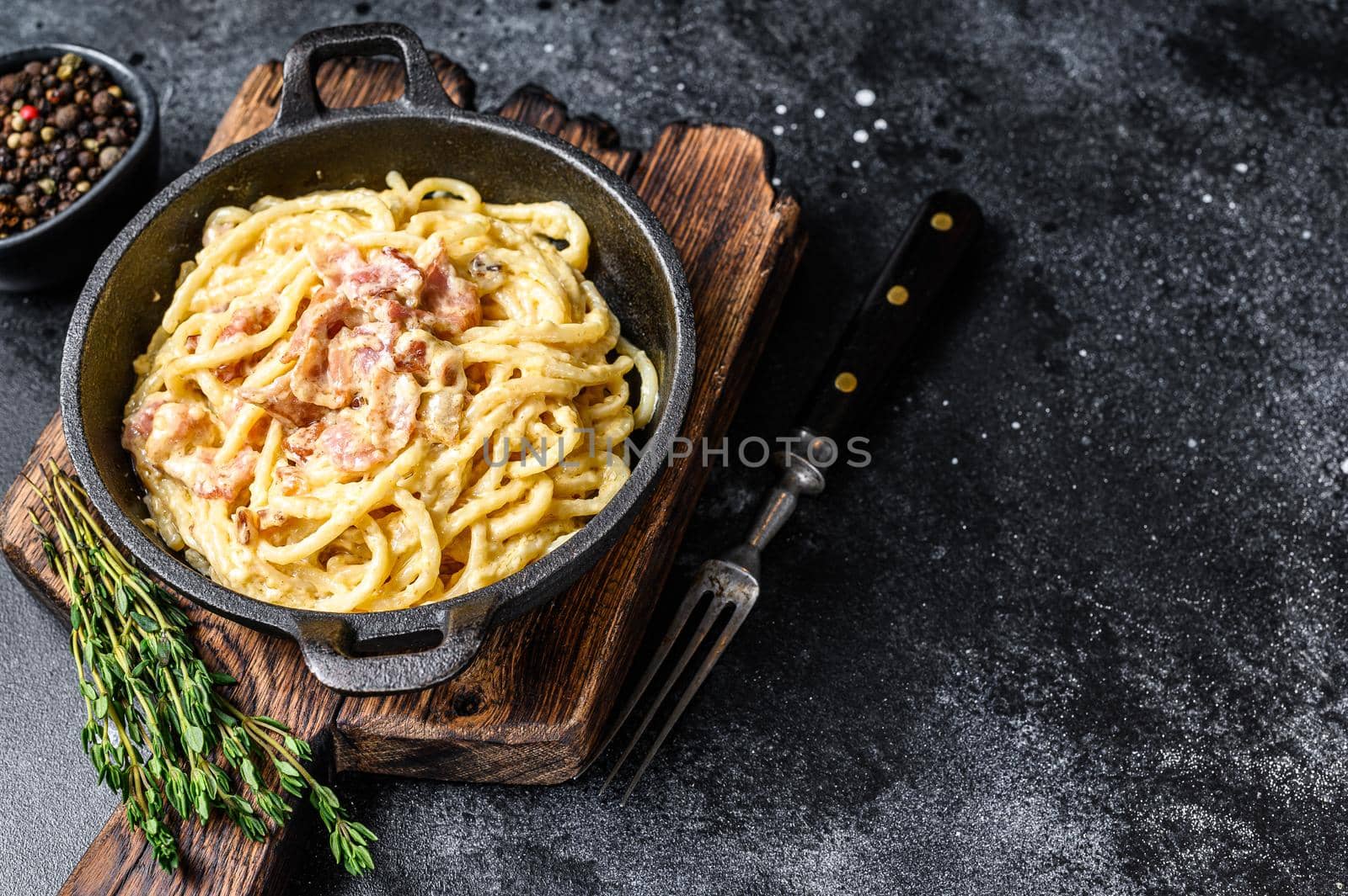 Pasta Carbonara with bacon and parmesan in a pan. Black background. top view. Copy space.