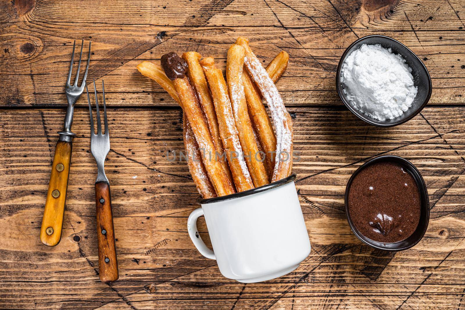 Churros with sugar and chocolate sauce. wooden background. Top view.