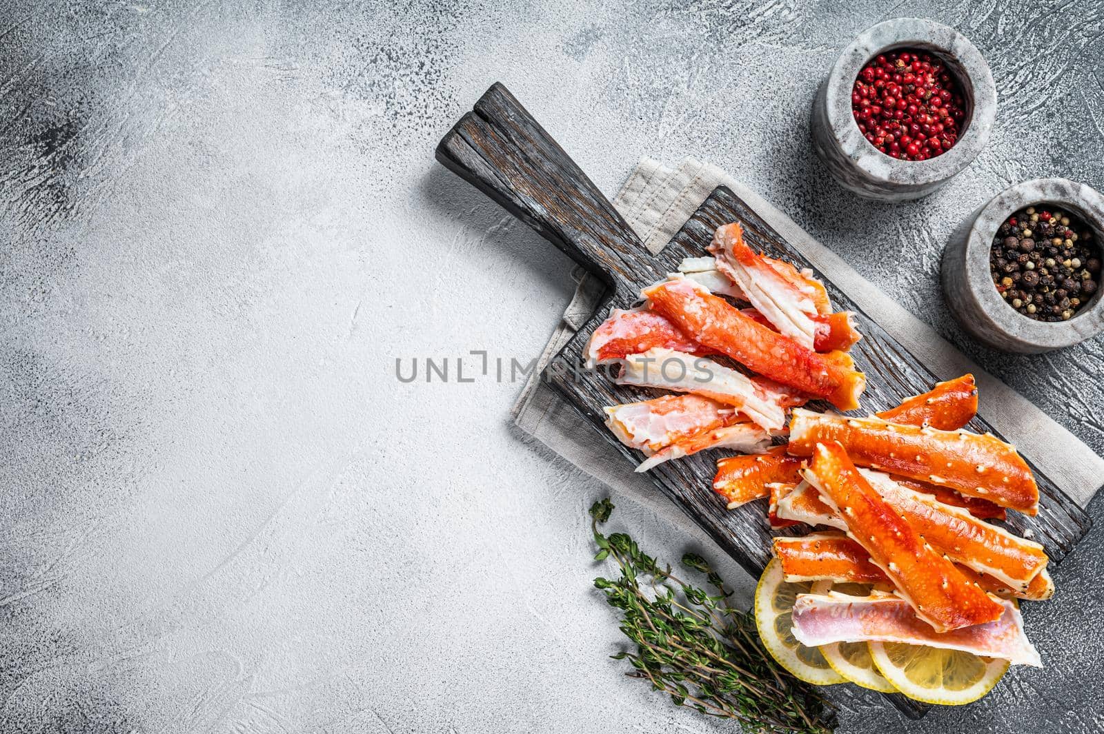 Cooked King Crab legs meat on a wooden board with herbs. White background. Top view. Copy space by Composter