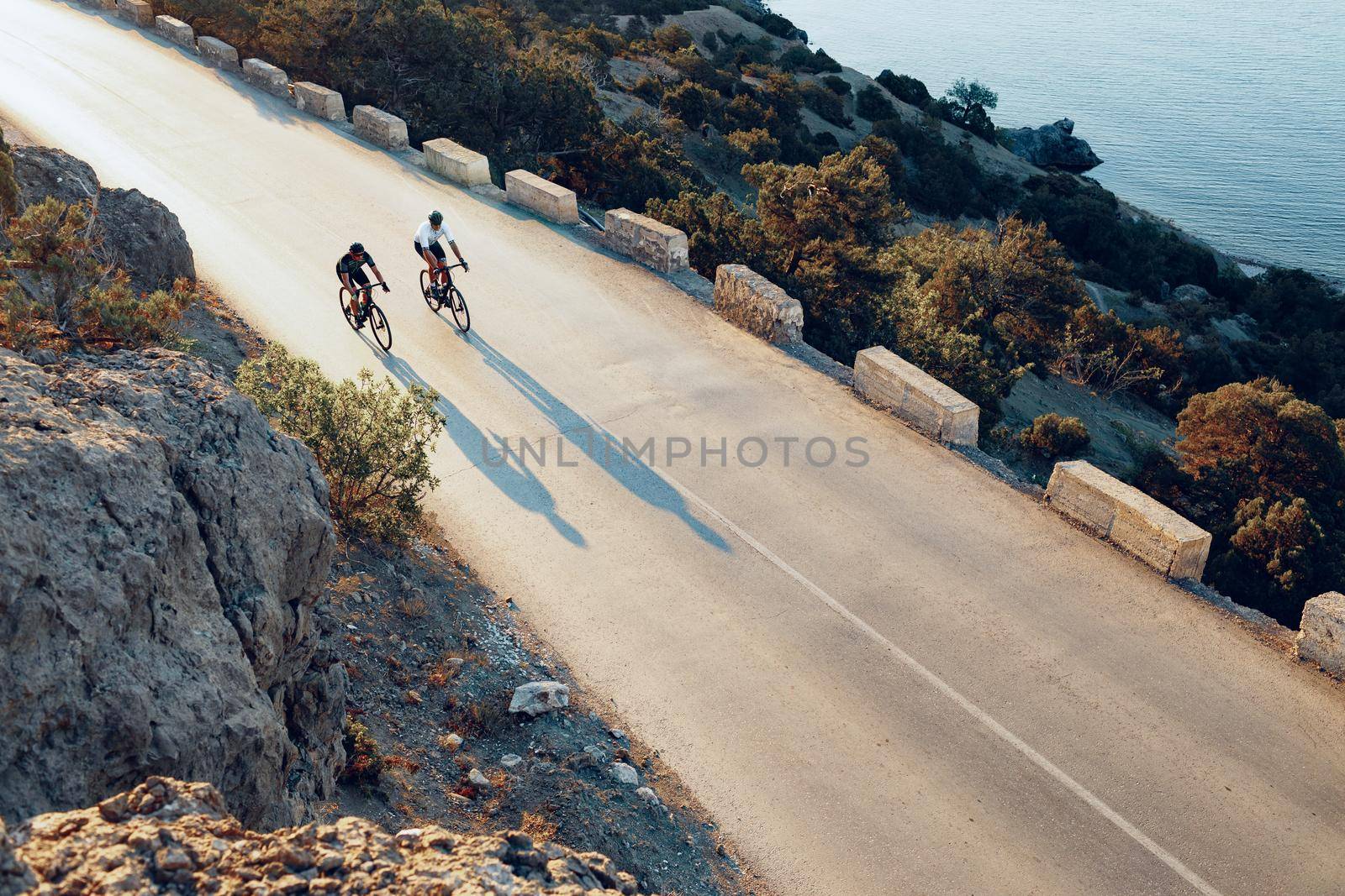 Two professional male cyclists riding their racing bicycles in the morning together on coastal road